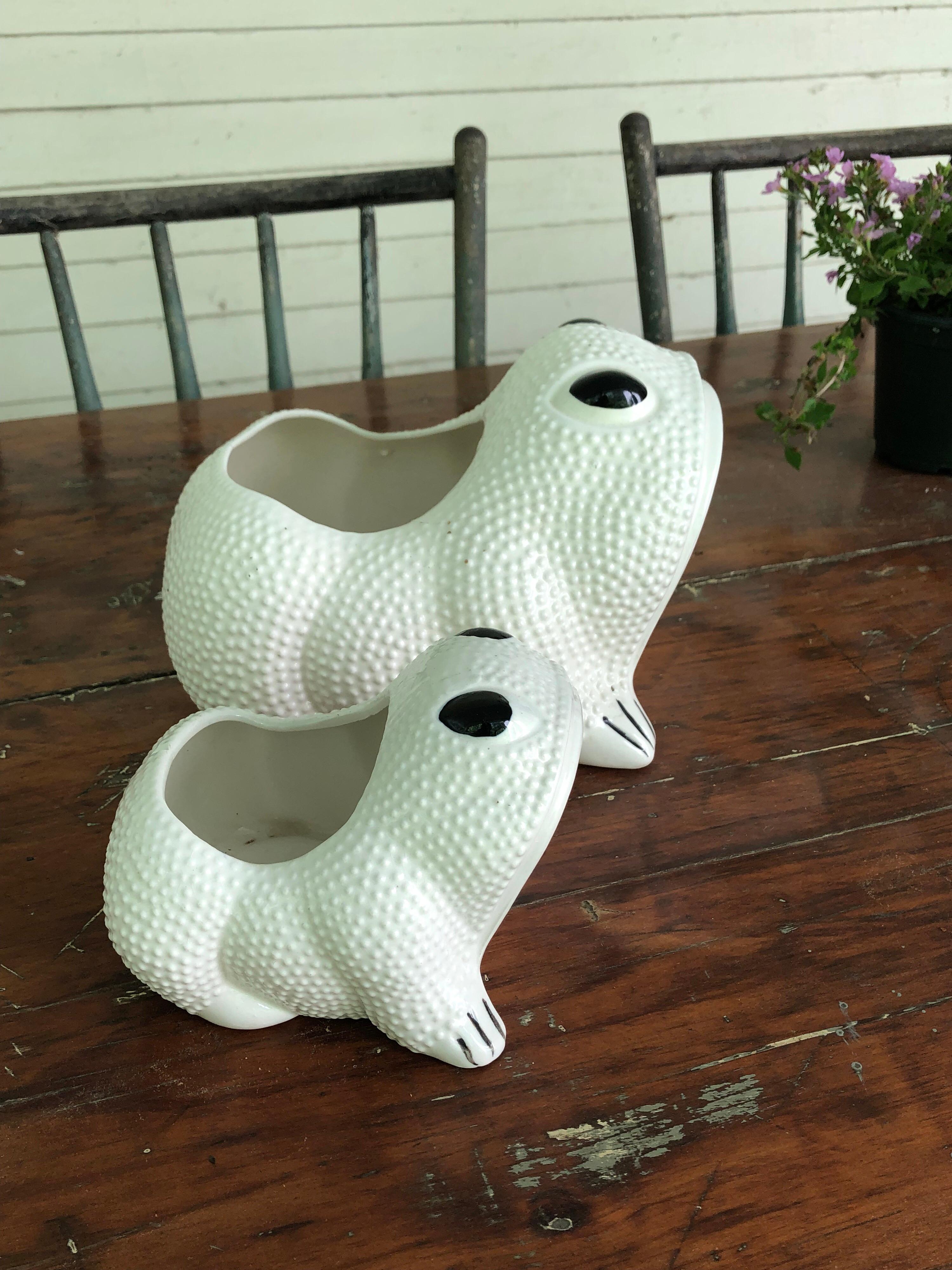 Two white toad form planters, hobnail like texture, each with bulging black eyes. Smaller one marked Japan, no markings on the larger one. The rage in the 1960s and 1970s, particularly the Southampton set. And Cal Alexander's store on Jobs Lane.