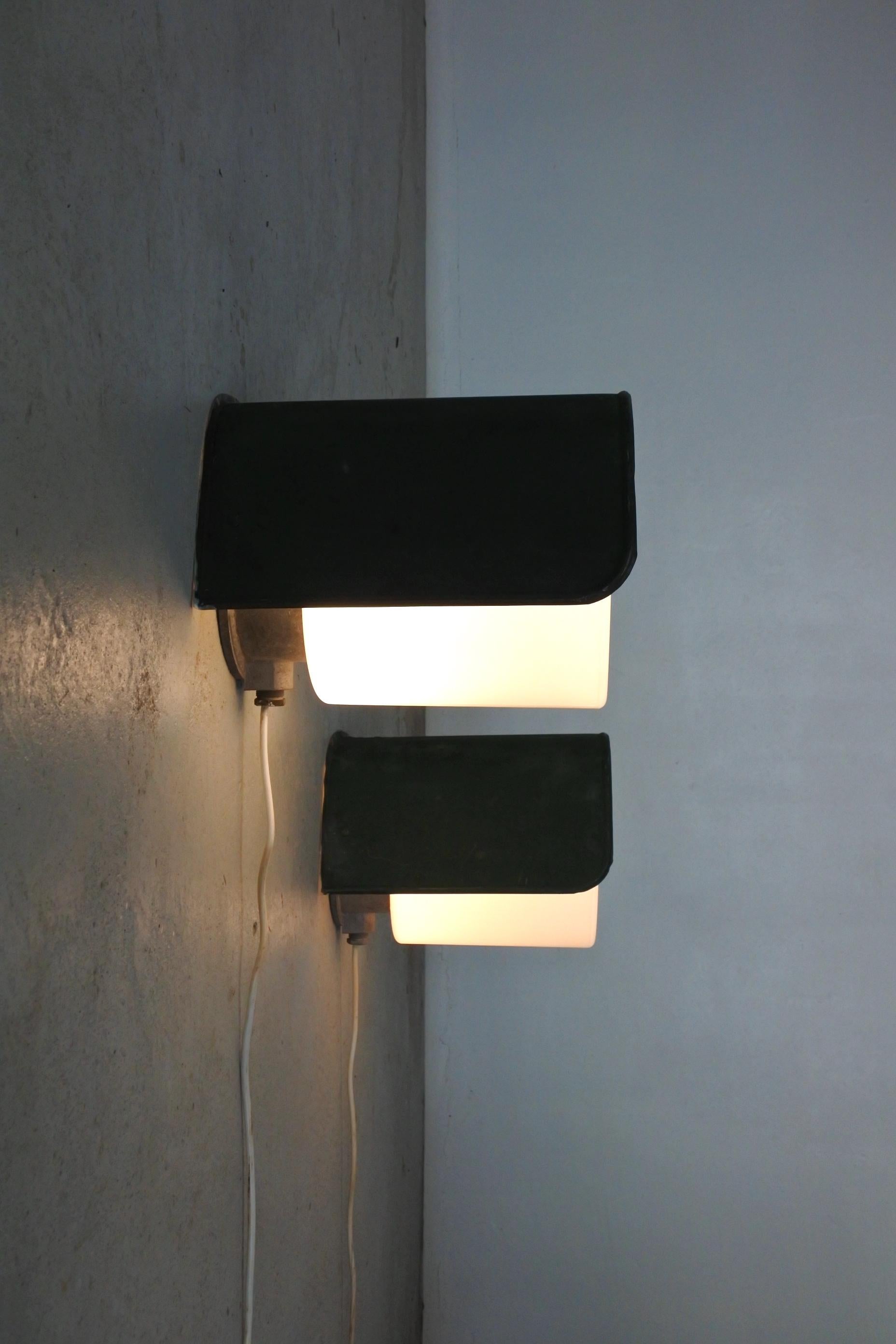 Set of 2 extra large wall lamps attributed to Idman.
Made in Finland in the 1950s.
Copper reflector and opaline glass cylinder mounted on an aluminium junction box.

Outstanding patina. Impressive dimensions. 

Could be used indoors or