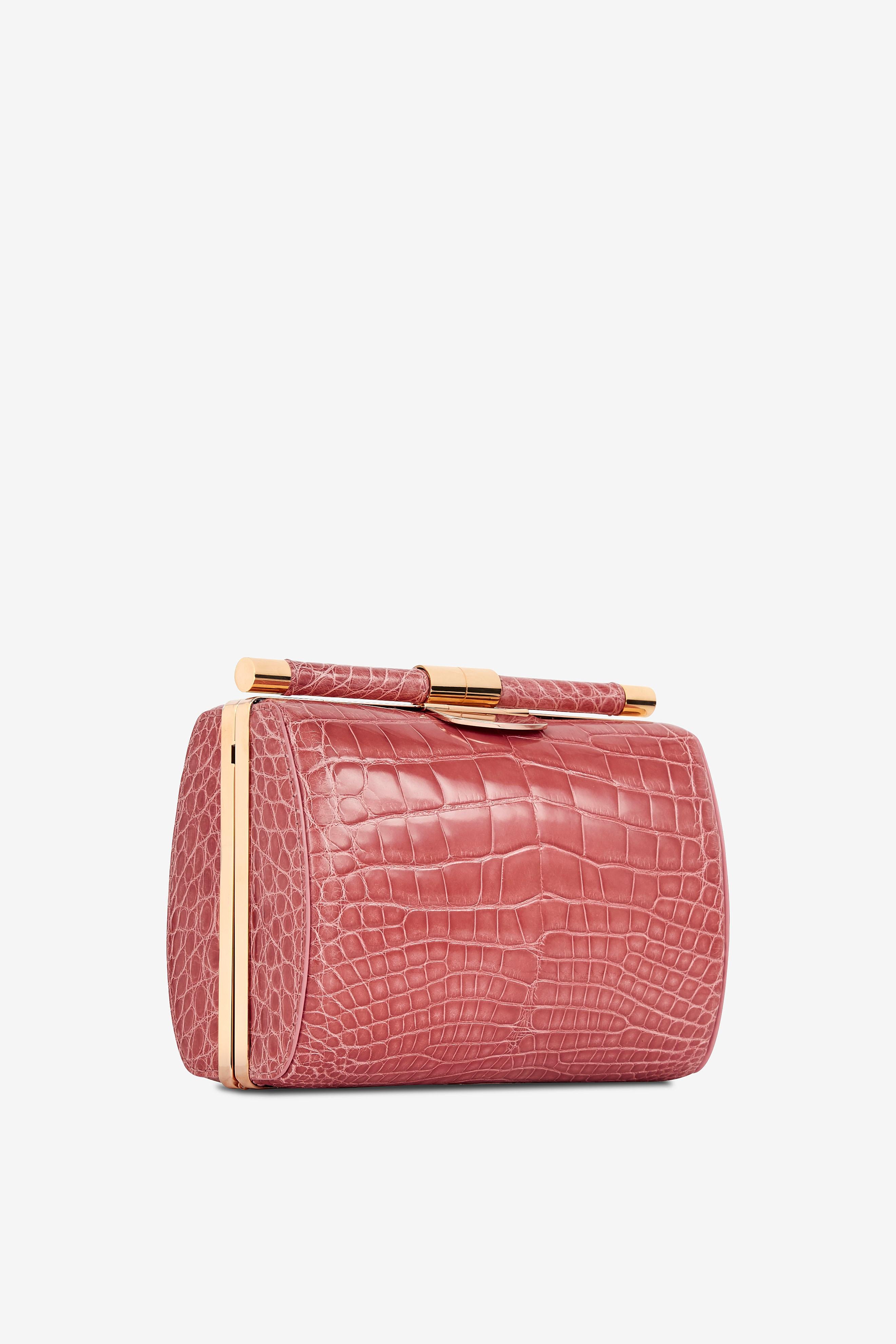 The Anjuli Clutch Medium Rose Alligator Rose Gold Hardware is a structured oval clutch, with an optional cross-body chain, and interior pocket. It features our signature slide-lock closure and Thayer blue satin lining. 

Size: Medium
Hardware: Rose