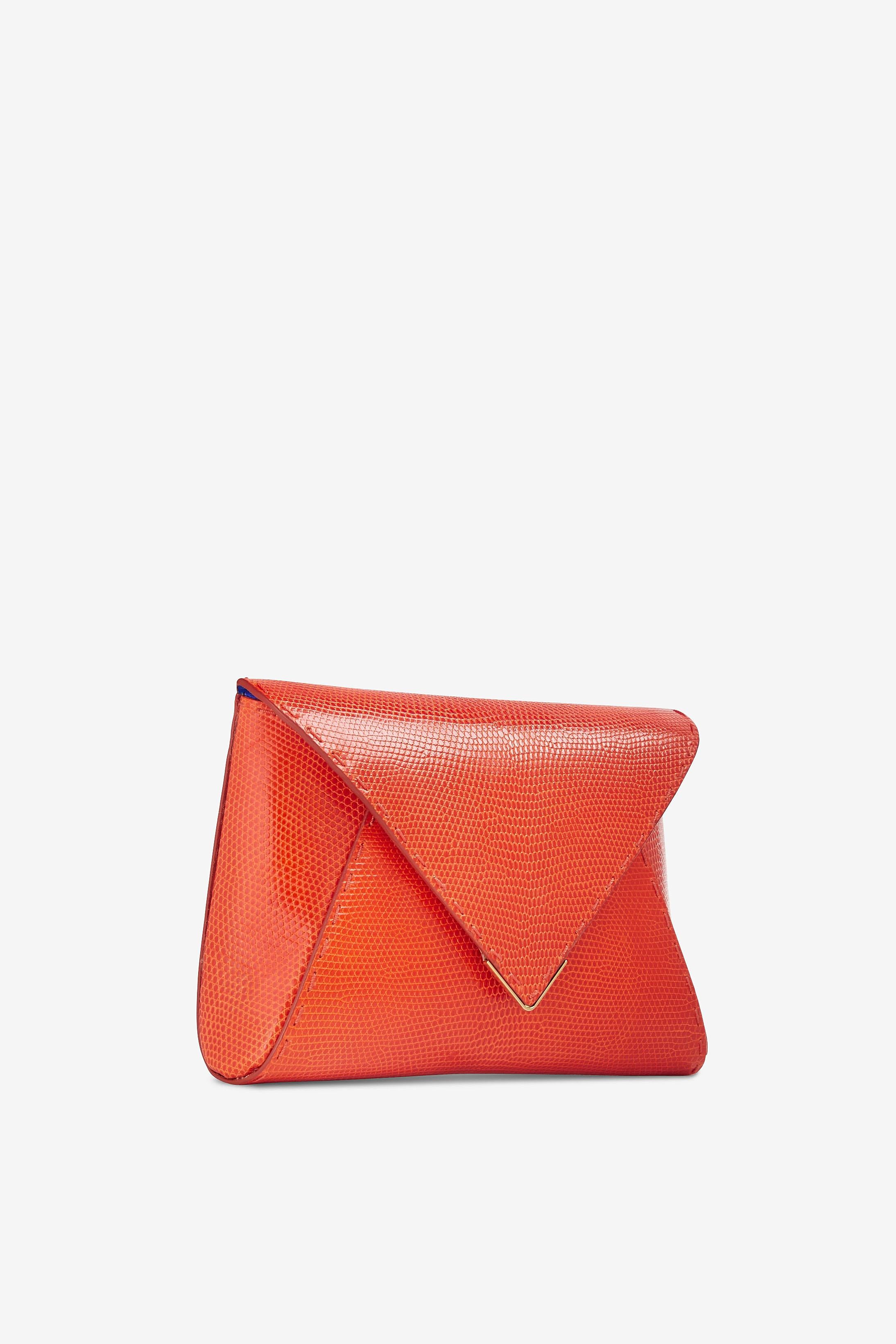 The Lee Pouchet Small Bright Orange Lizard Gold Hardware is a soft clutch designed with a triangular front flap and a magnetic closure. The exterior detailing is entirely hand-stitched. It features a hidden exterior pocket, a detachable gold