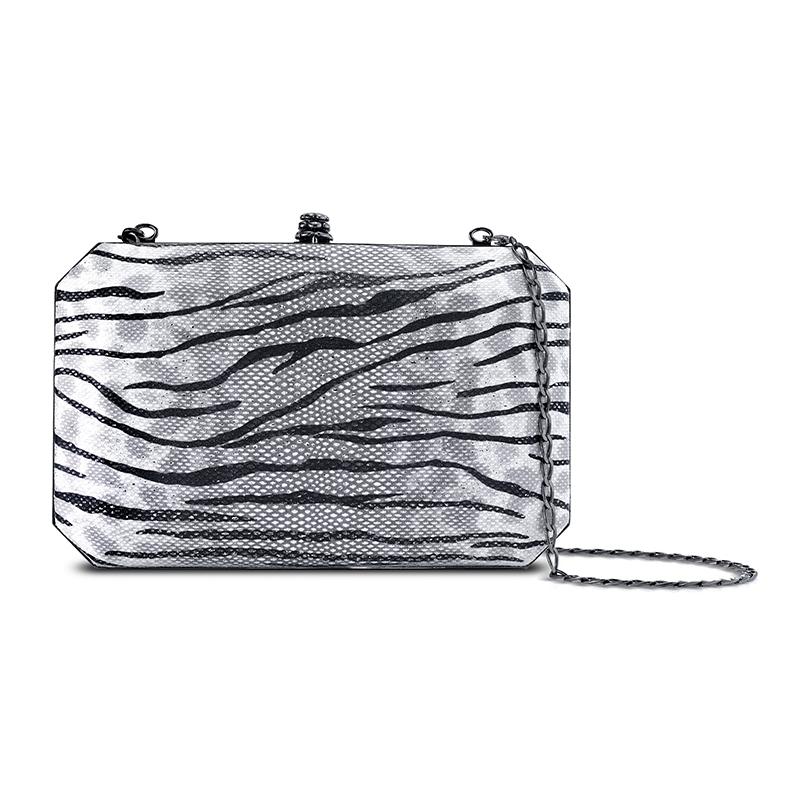 The Lily in Metallic Silver Tiger Karung is a hard-framed rectangular clutch designed with interior pockets and an optional gunmetal cross-body chain. It fits the large iPhone and features our signature Pinecone Closure and Thayer Blue