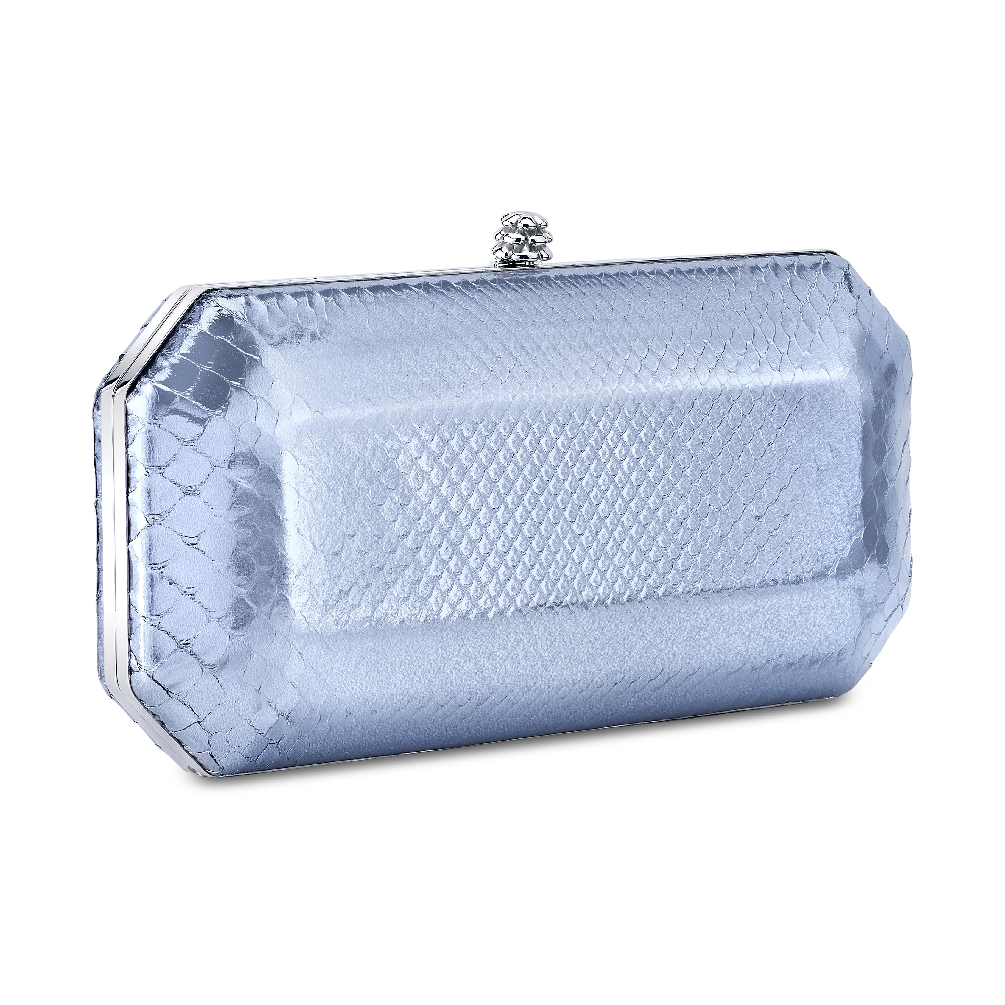 The Perry in Glacier Blue Python is a hard-framed clutch designed with interior pockets and an optional silver cross-body chain. Its elegant emerald shape is inspired by Tyler’s own engagement ring and named after her father, Perry Ellis. It fits