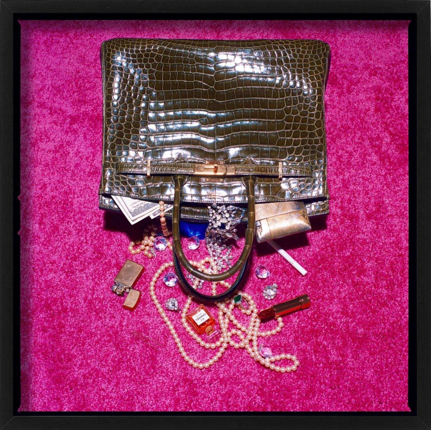 Eine Birkin-Tasche ist umgekippt und hat ihren gesamten Inhalt über den rosa Teppich verteilt, fotografiert von Tyler Shields. 

Alle Drucke sind in limitierter Auflage erhältlich. Erhältlich in mehreren Größen. Hochwertige Einrahmung auf