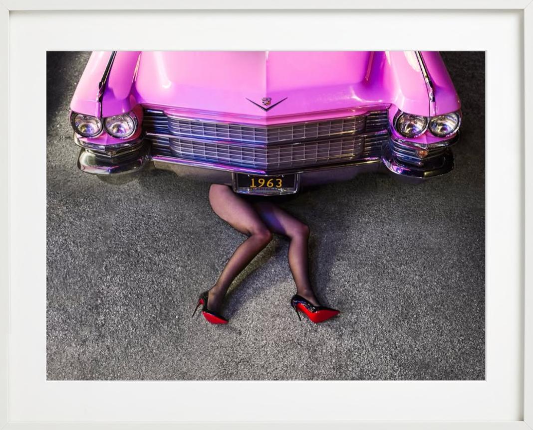 Cadillac Legs - Frau in Heels unter rosa Auto liegend, Kunstfotografie 2025 (Zeitgenössisch), Photograph, von Tyler Shields