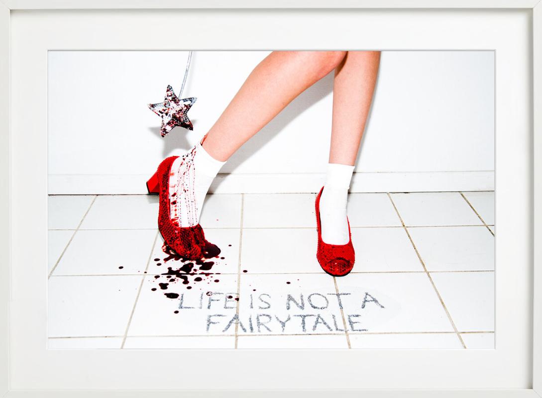 Das Leben ist kein Märchen, geschrieben auf einem weißen Fliesenboden, der wie ein Badezimmerboden aussieht, mit roten, glitzernden, funkelnden Schuhen und einer Hand, die einen Zauberstab hält, fotografiert von Tyler Shields im Jahr 2021. 

Alle
