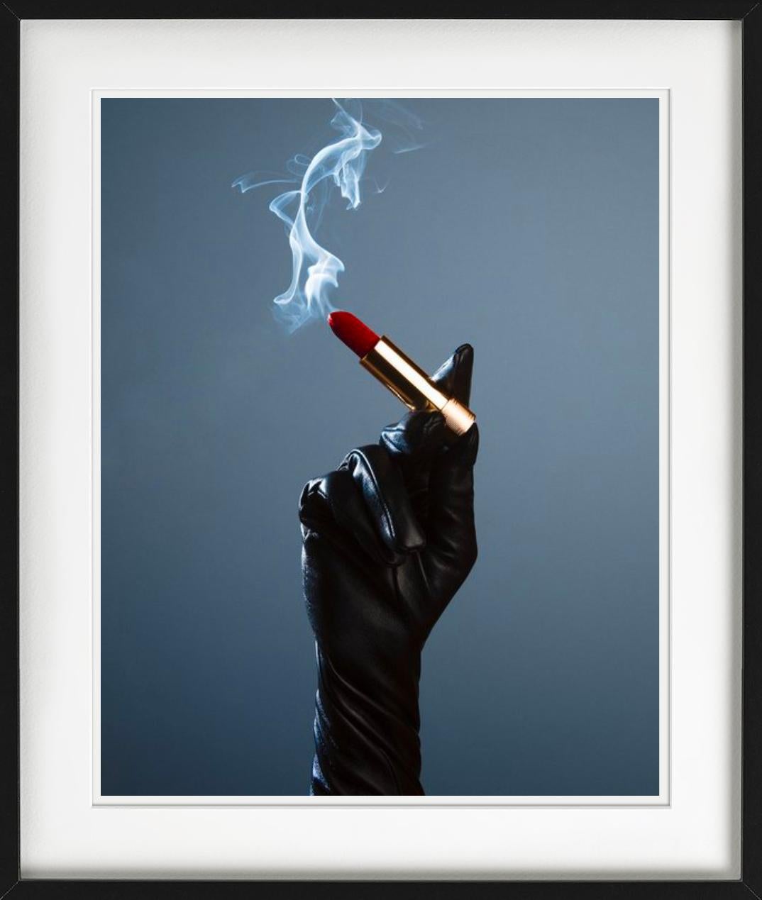 Mit einem schwarzen Handschuh bedeckte Hand, die einen rauchenden Lippenstift wie eine Zigarette hält, fotografiert von Tyler Shields im Jahr 2022. 

Alle Drucke sind in limitierter Auflage erhältlich. Erhältlich in mehreren Größen. Hochwertige