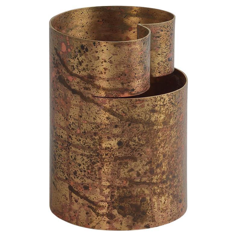 This remarkable brass vase displays a slender silhouette with a crescent-like profile only interrupted by a flat plate welded on the front. The various metal parts get cut, welded together, and finally undergo the traditional etching process, for a