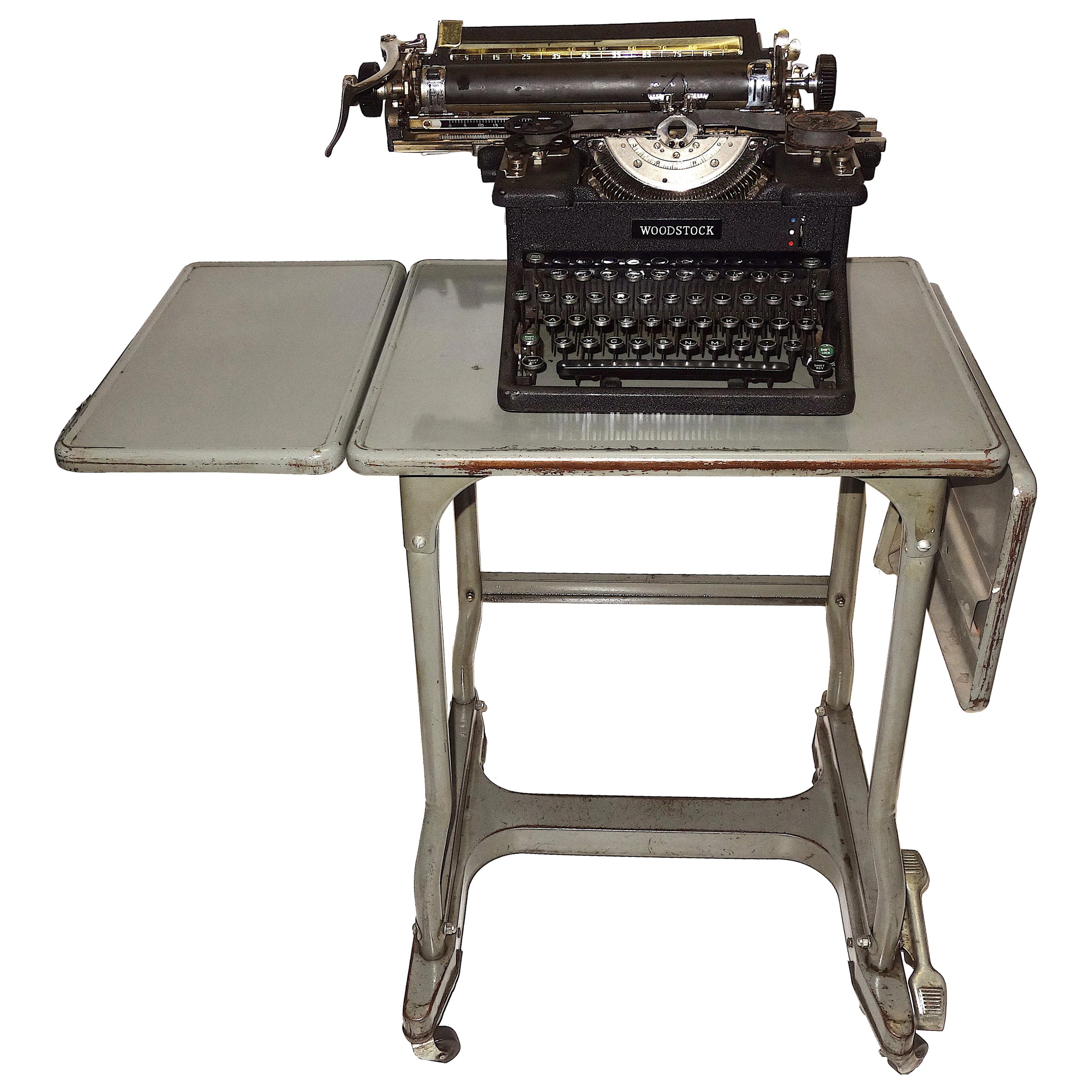 Offered for your consideration is this iconic, working, circa 1920s woodstock vintage typewriter displayed on a vintage steel typewriter drop-leaf rolling table.
Woodstock was based near Chicago and started out as the Emerson Brand, then the