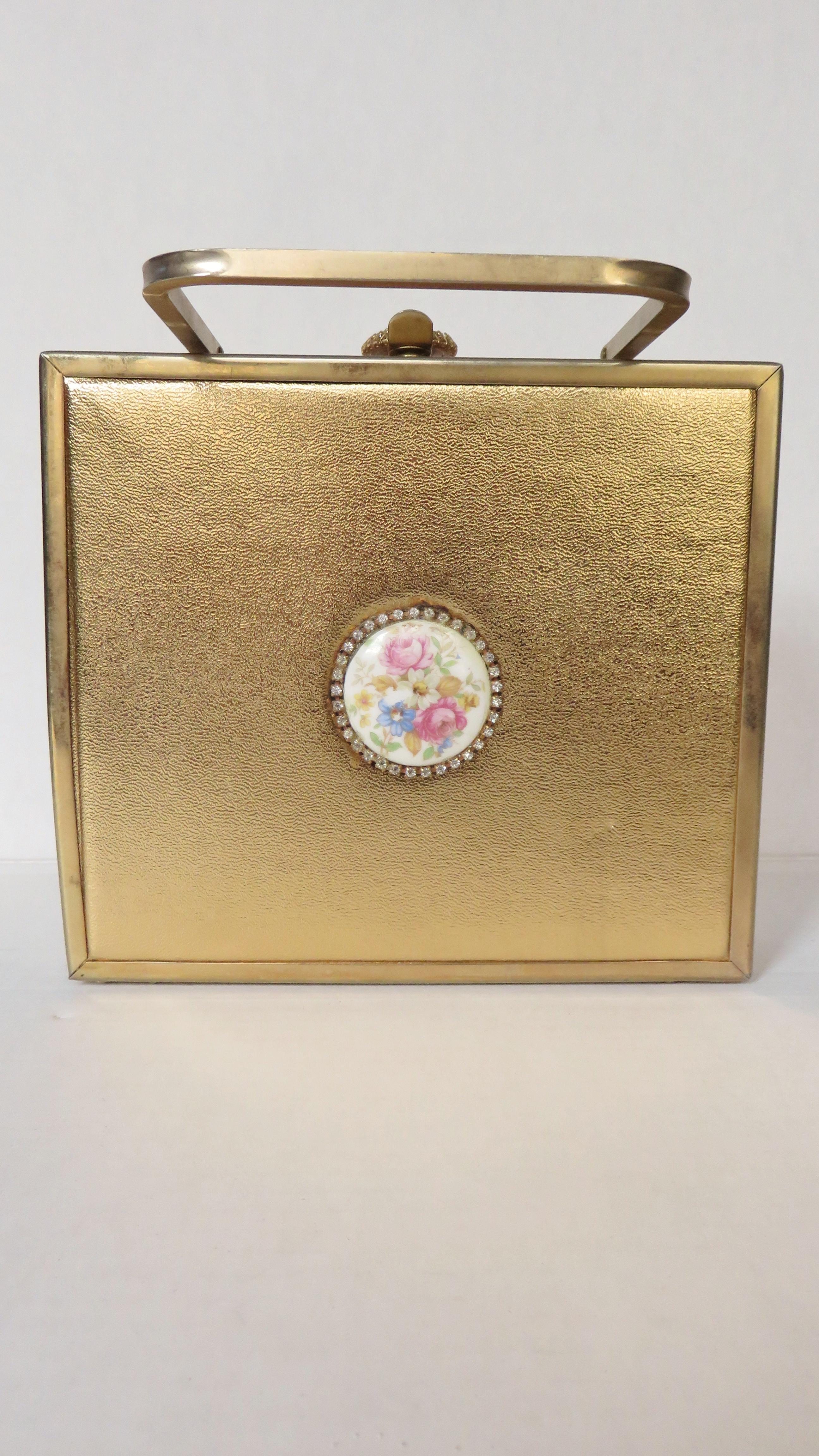 A fabulous gold box purse from Tyrolean.  It is square with a gold rounded square metal top handle and rhinestone framed circular flowered 2