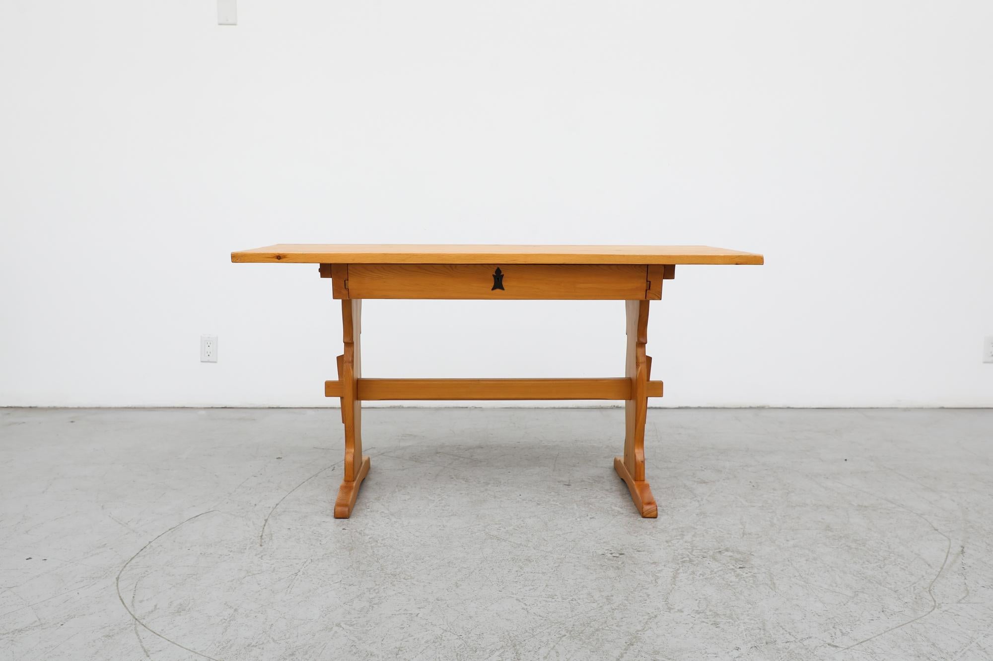 Beautiful, almost folkloristic, Tyrolean style desk with pine wood frame and lower locking drawer. Organically carved, its traditional features in natural wood tone are contrasted by an ornate black iron key accent. The 