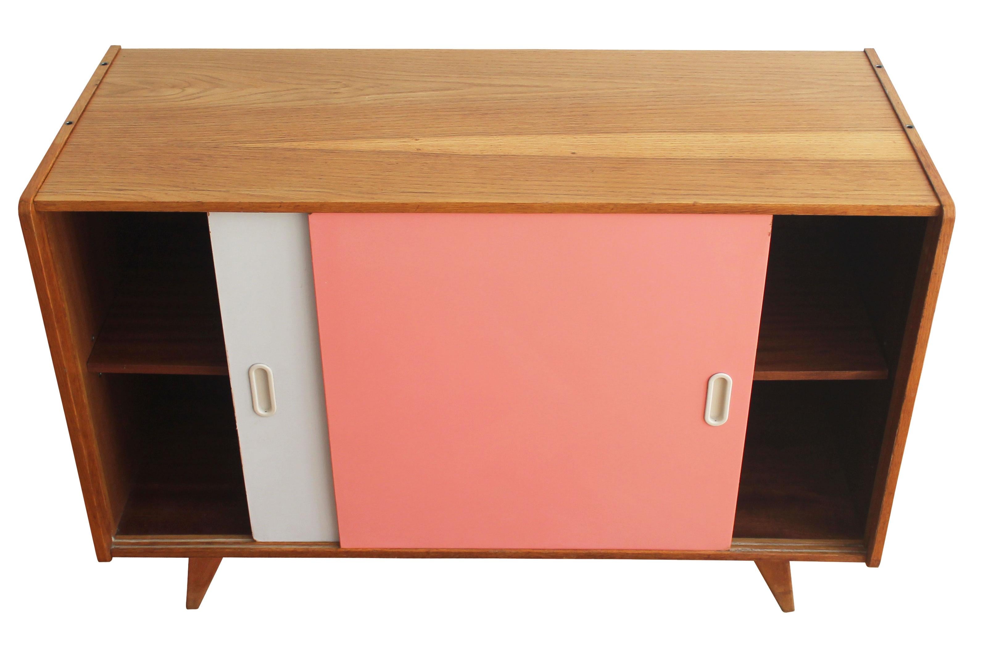 The U-452 mid-century sideboard with pink and white sliding doors, was designed by the Czech furniture designer Jiri Jiroutek. It is part of the popular U collection manufactured by Interier Praha in the 1960s Czechoslovakia. 

This piece