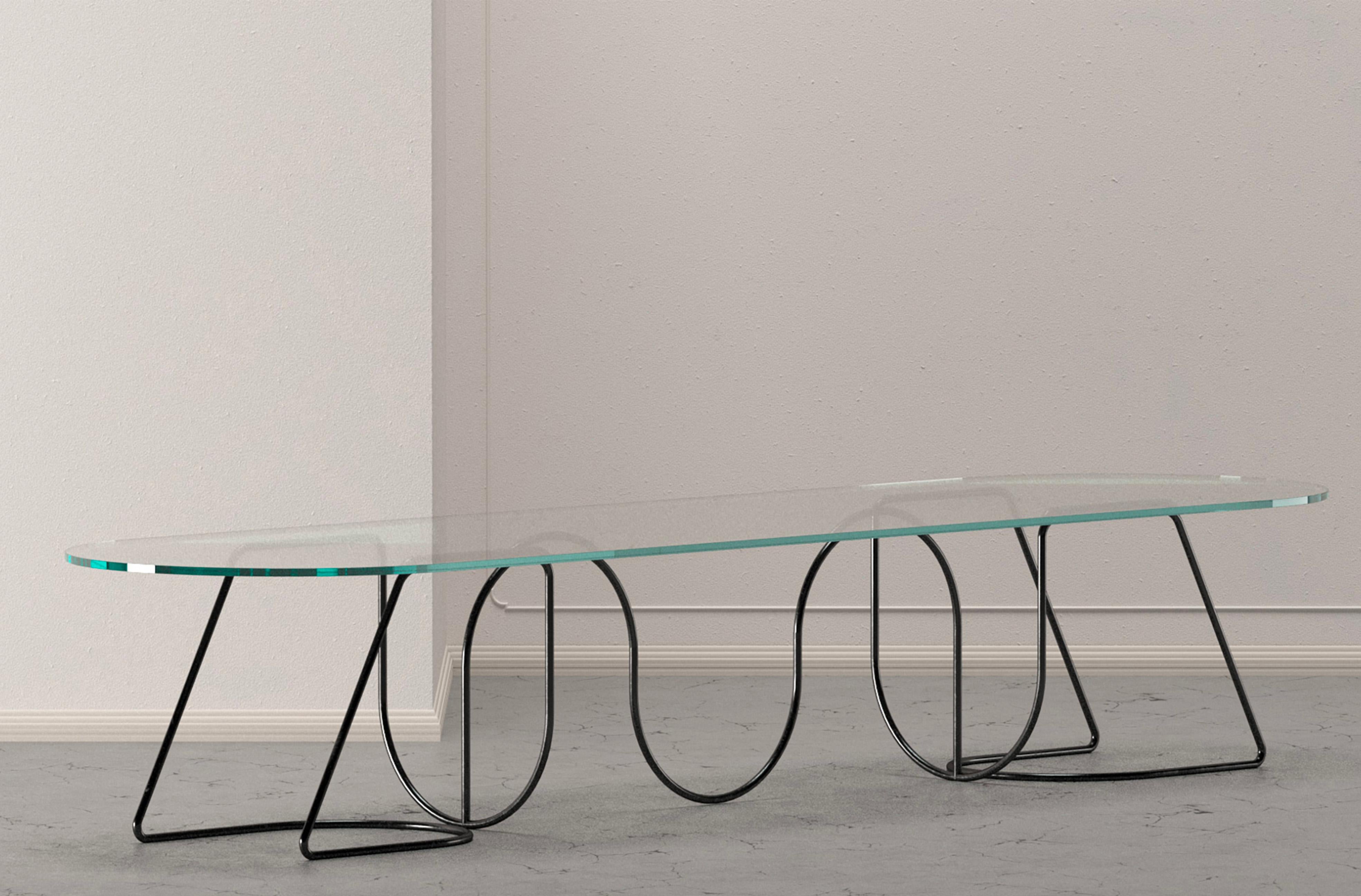 A splendid addition to contemporary-style decors, this refined table stands out for the intricate and sculptural base in cylindrical steel. A wide transparent glass top with rounded sides sits atop the base, allowing the dynamic design underneath to