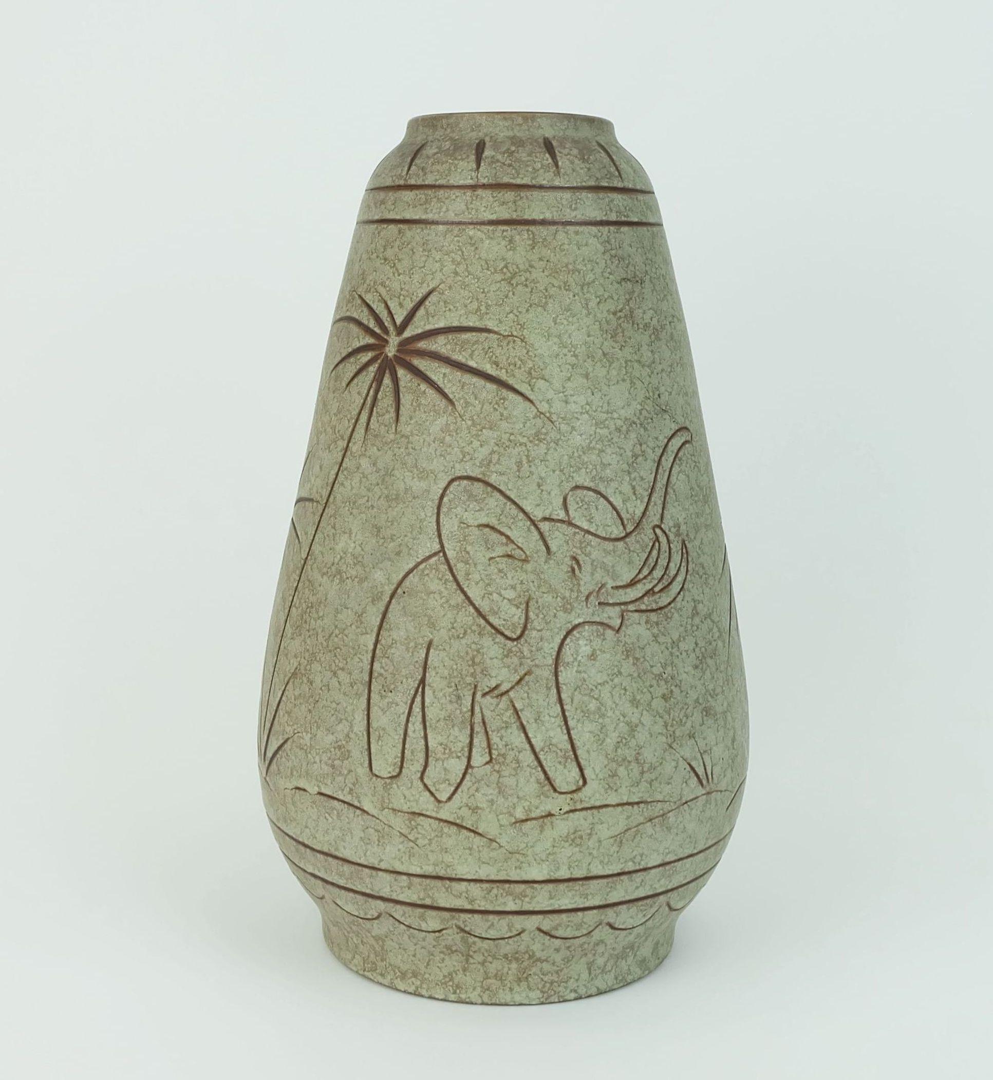 Un bellissimo vaso vintage prodotto da u-Keramik nei primi anni '60. Disegno di elefanti e palme in tecnica sgraffito. Model No. 137/30. 

Dimensioni in cm:
Altezza 30 cm, diametro maggiore 18 cm.

Dimensioni in pollici:
Altezza 11,81
