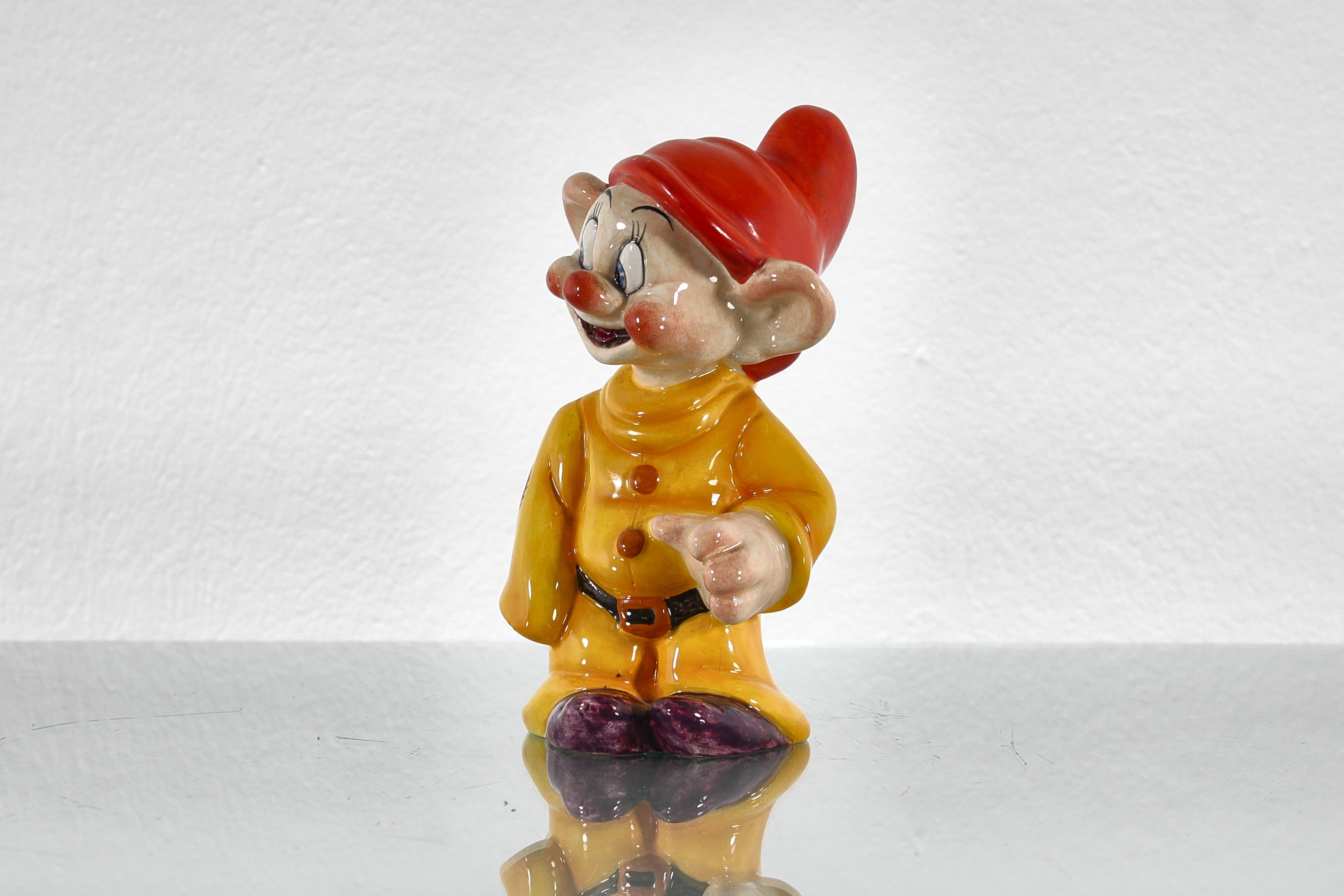 Miniatur, signiert Ugo Zaccagnini, aus handglasierter Keramik, die den Zwerg Dopey aus Schneewittchen und die sieben Zwerge von Walt Disney darstellt. Italienische Produktion aus den 1940er Jahren. Unterschrift auf der Unterseite.
Alters- und