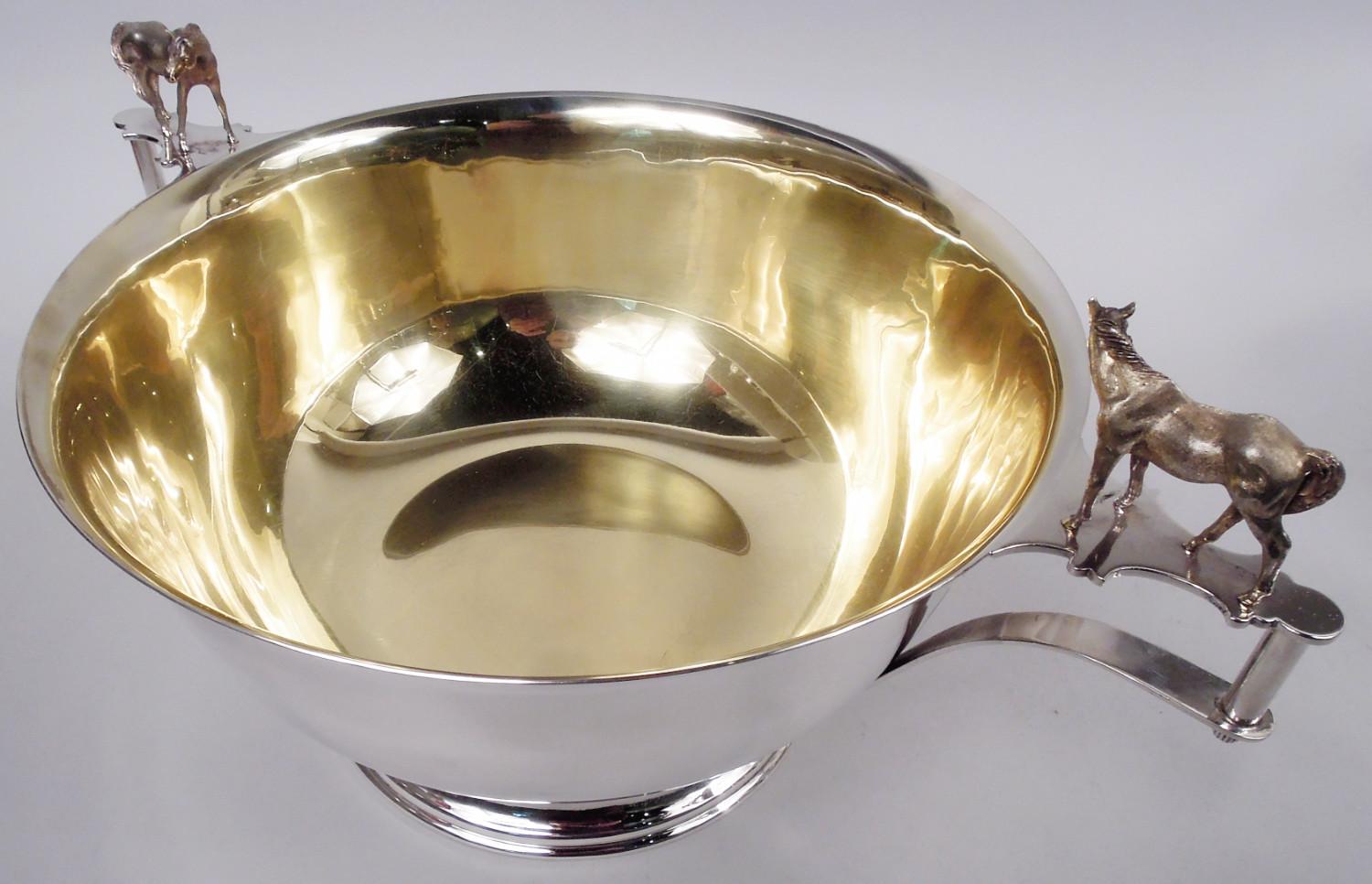 Große Trophäenschale aus klassischem Sterlingsilber. Rund und gewölbt mit ausgestelltem Rand und gestuftem und gewölbtem Fuß. Seitliche Bügelgriffe mit Kistenpferdfiguren, die an geformten Stützen befestigt sind. Vergoldetes Interieur. Viel Platz