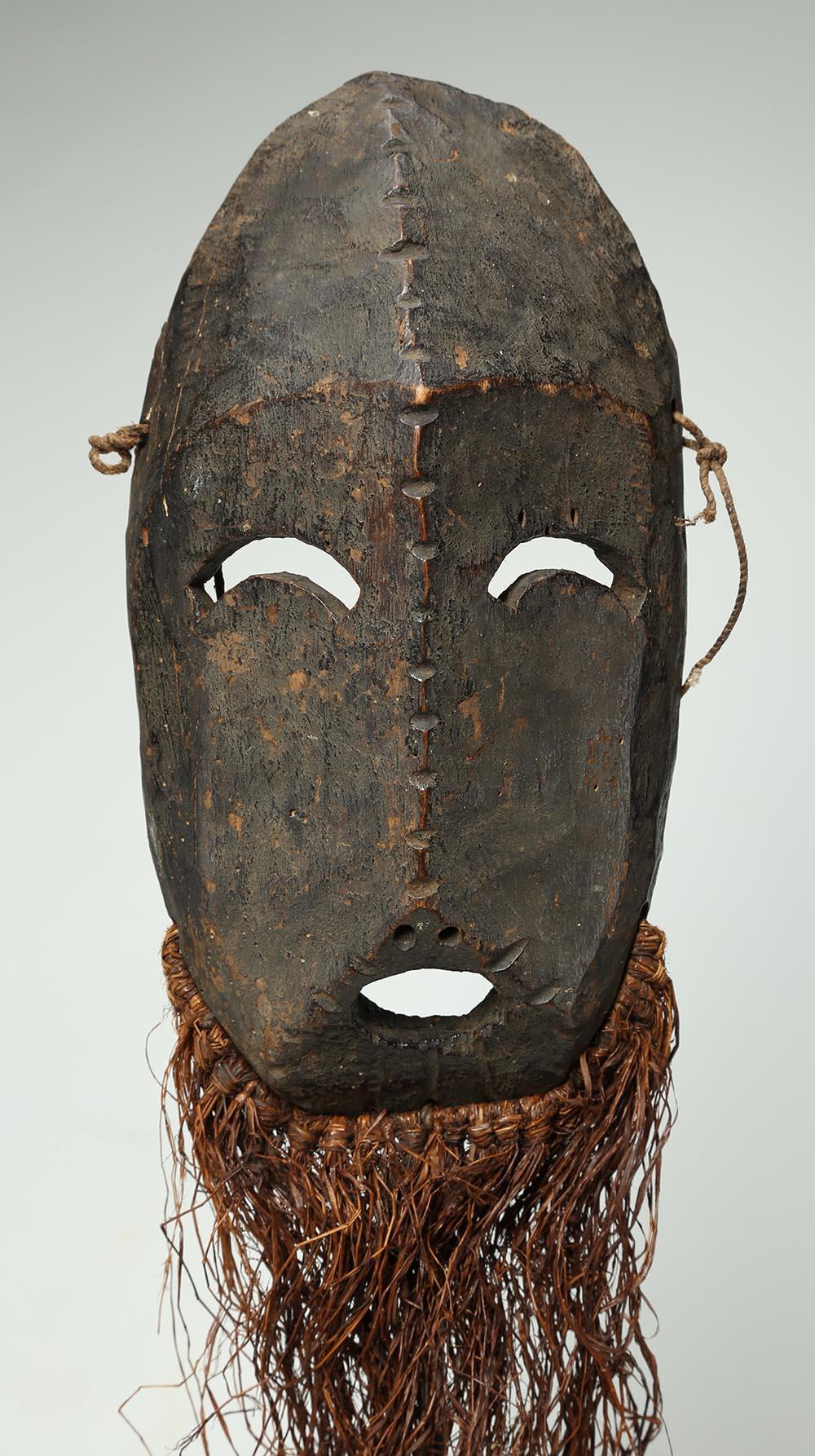 A wonderfully expressive Ubangi region of the Democratic Republic of Congo carved wood mask with beard, early 20th century, Africa. Downward curved eyes and notched scarification up forehead and down nose, open mouth and raffia beard. Old wear and