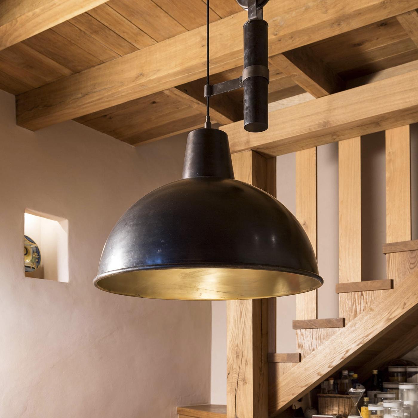 This striking suspension lamp is made in burnished brass on the outside and natural brass on the inside. It features a pulley and counterweight system fixed to the ceiling with a burnished brass plate. A beautiful addition to any home, this lamp