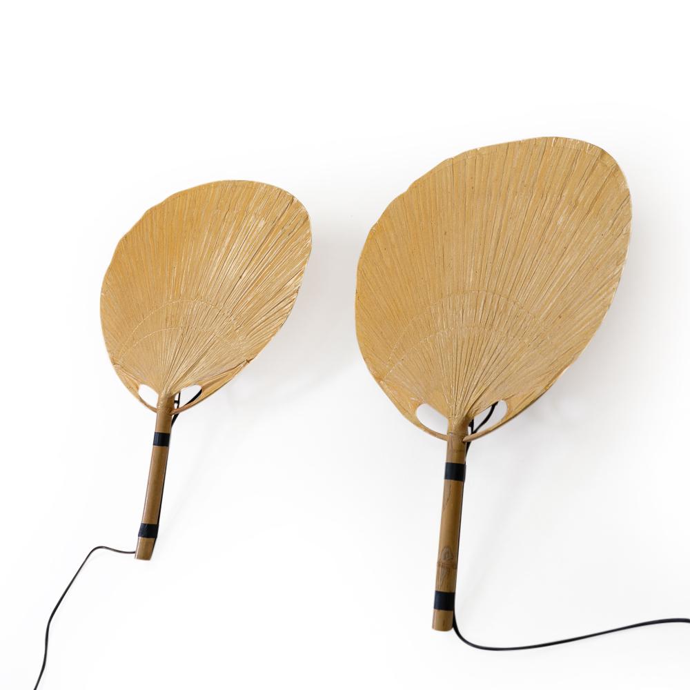 A matching pair of Uchiwa wall lamps by Ingo Maurer produced by his company Design M during the late 1970s in Germany.

The lamps are made from rice paper on a bamboo stem. Fits an E27 bulb, suitable for US voltage after changing the plug or using a