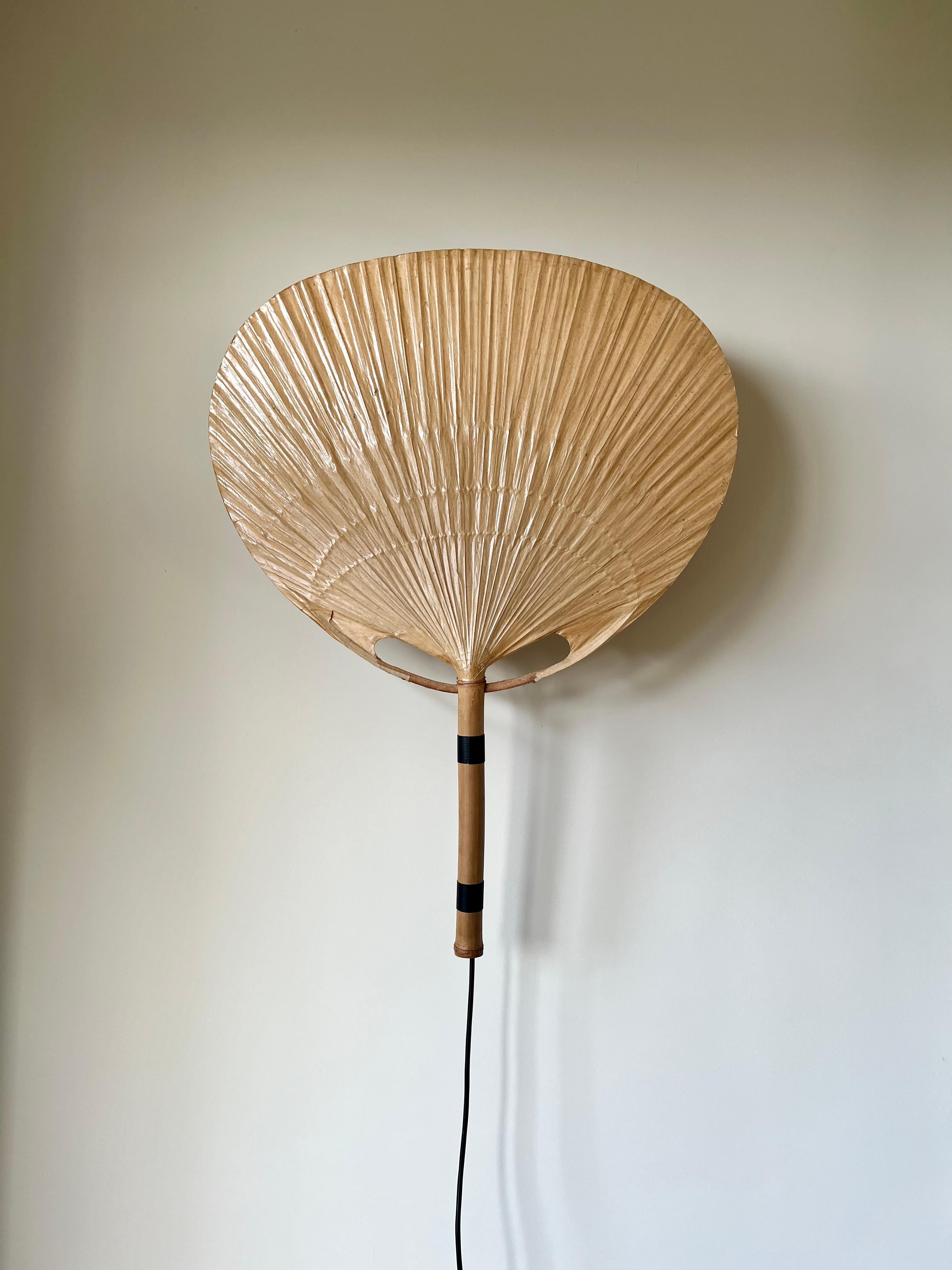 Uchiwa fan wall light designed in the 1970s by Ingo Maurer for his Munich based lighting design company, M-Design.

This delicate light is made from bamboo and laminated paper using traditional Japanese techniques.

Very good condition, with a