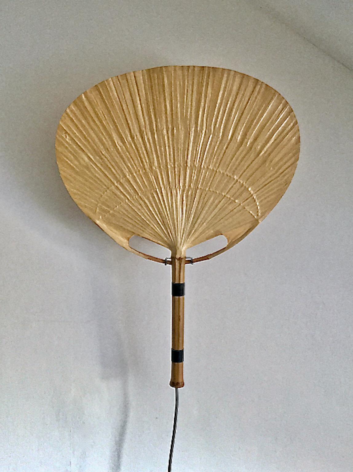 An “Uchiwa” wall light by Ingo Maurer (1932 to 2019) for M design, Germany, 1970s. Smaller wall model (46cm wide).

Beautiful understated design composed of rice paper and bamboo, which gives a beautifully warm and diffuse glow. Unusual to see in