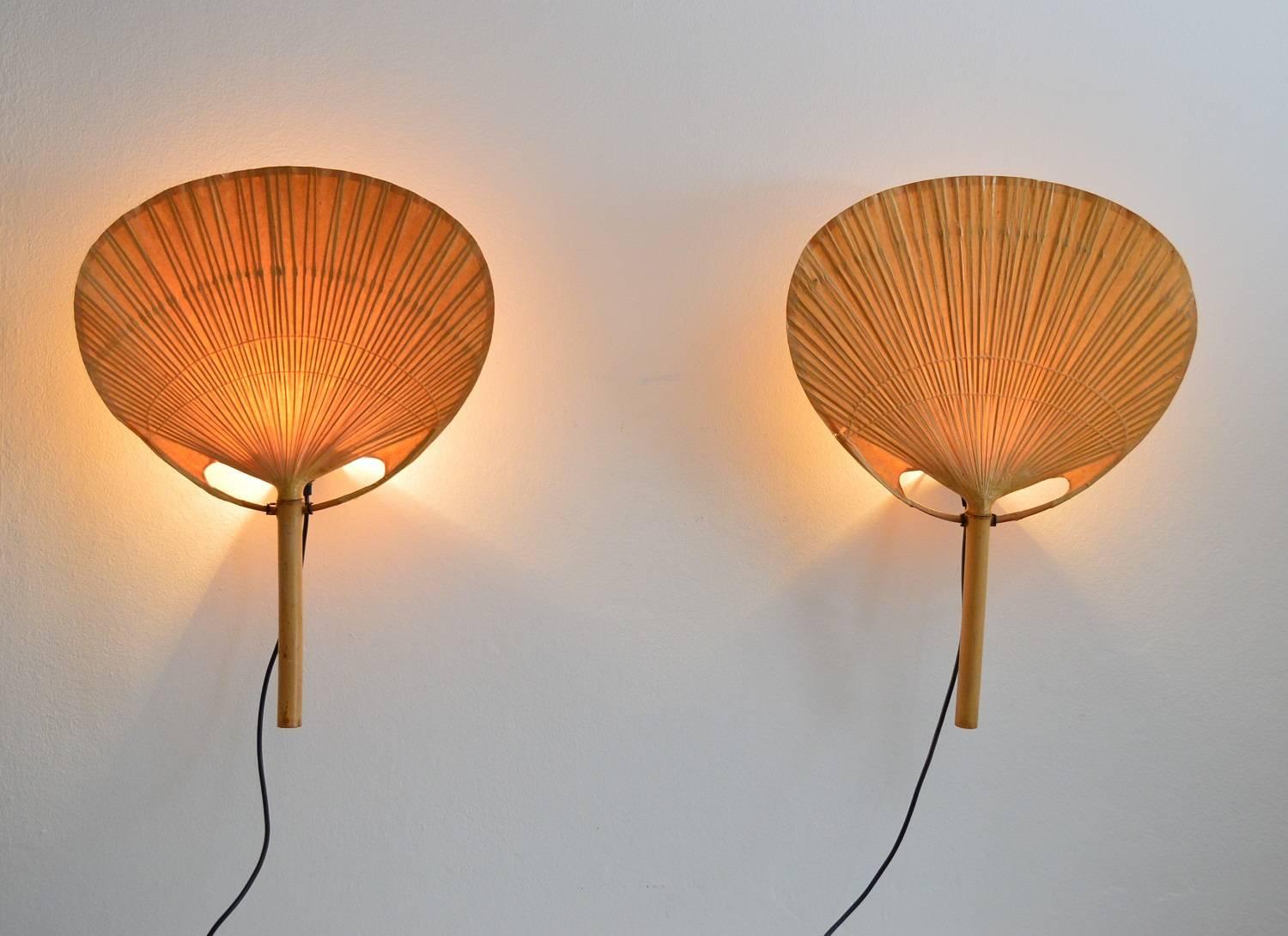 Beautiful set of two pieces of Ingo Maurer Uchiwa fan lamps with metal holder for wall hanging.
The fans are made by artisan of natural bamboo and rice paper in the 1970s, therefore both lamps are a little different from each other.
The metal