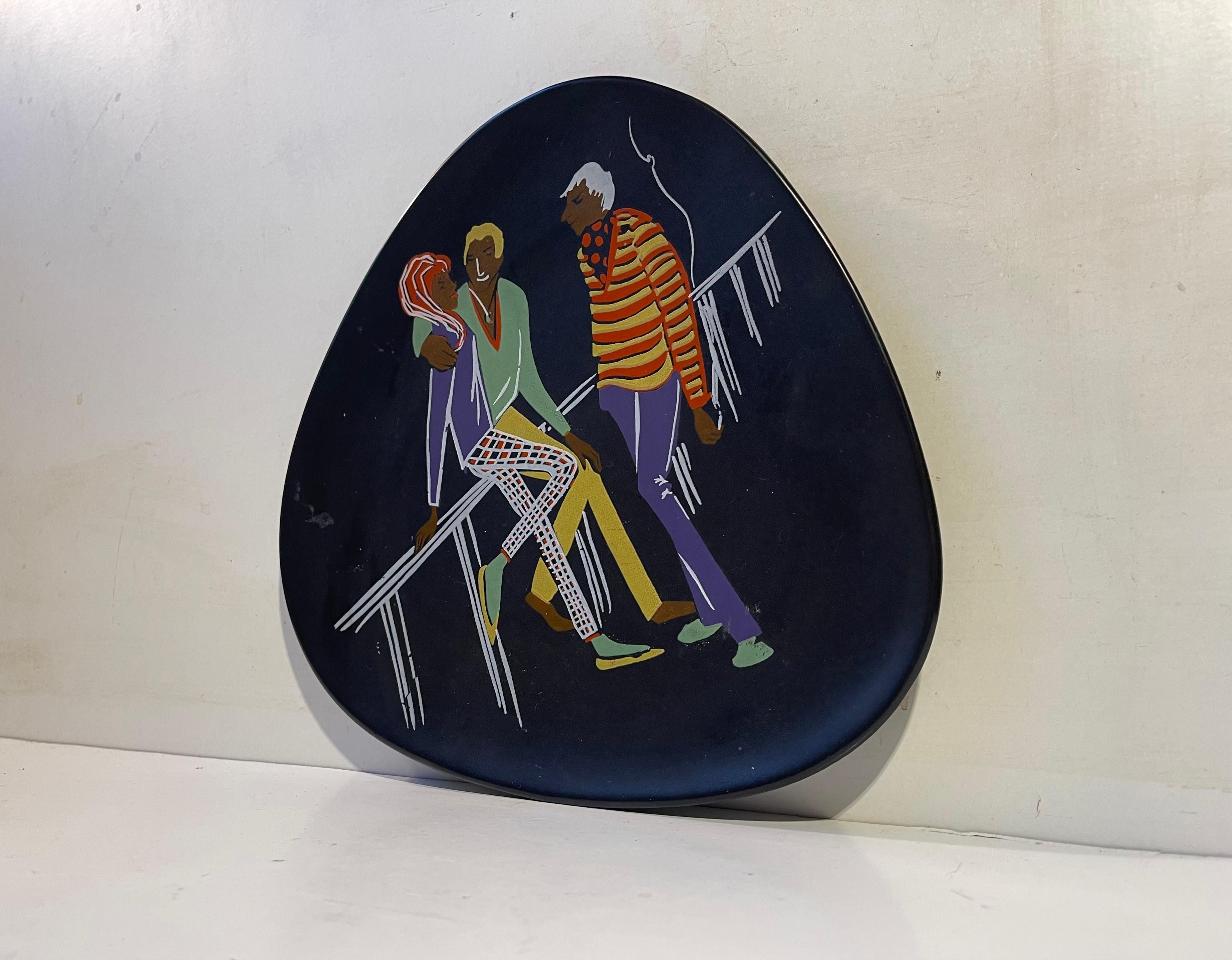 Boheme Fashionista black palet shaped dish or plate decorated with 3 young people dressed in vibrant color. Designed and made at Üebelacker Kermit in West Germany during the 1950s or 60s. Very similar to designs from Keto Keramik and Hans Welling in