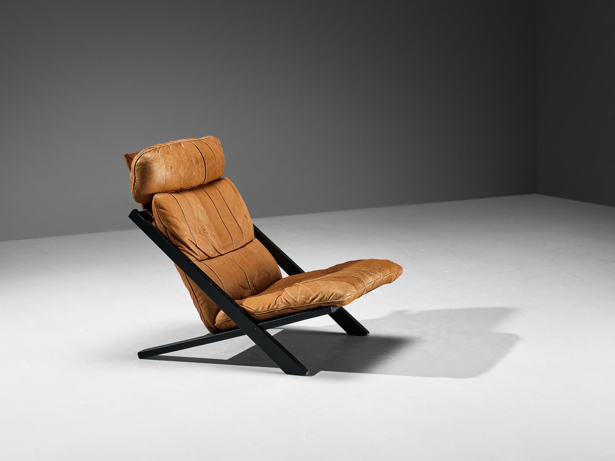 Ueli Berger for De Sede, lounge chair, wood, leather, Switzerland, 1970s

High back lounge chair by Swiss manufacturer De Sede. The X-shaped frame consists of black lacquered wood. This makes an interesting contrast to the warm patinated cognac