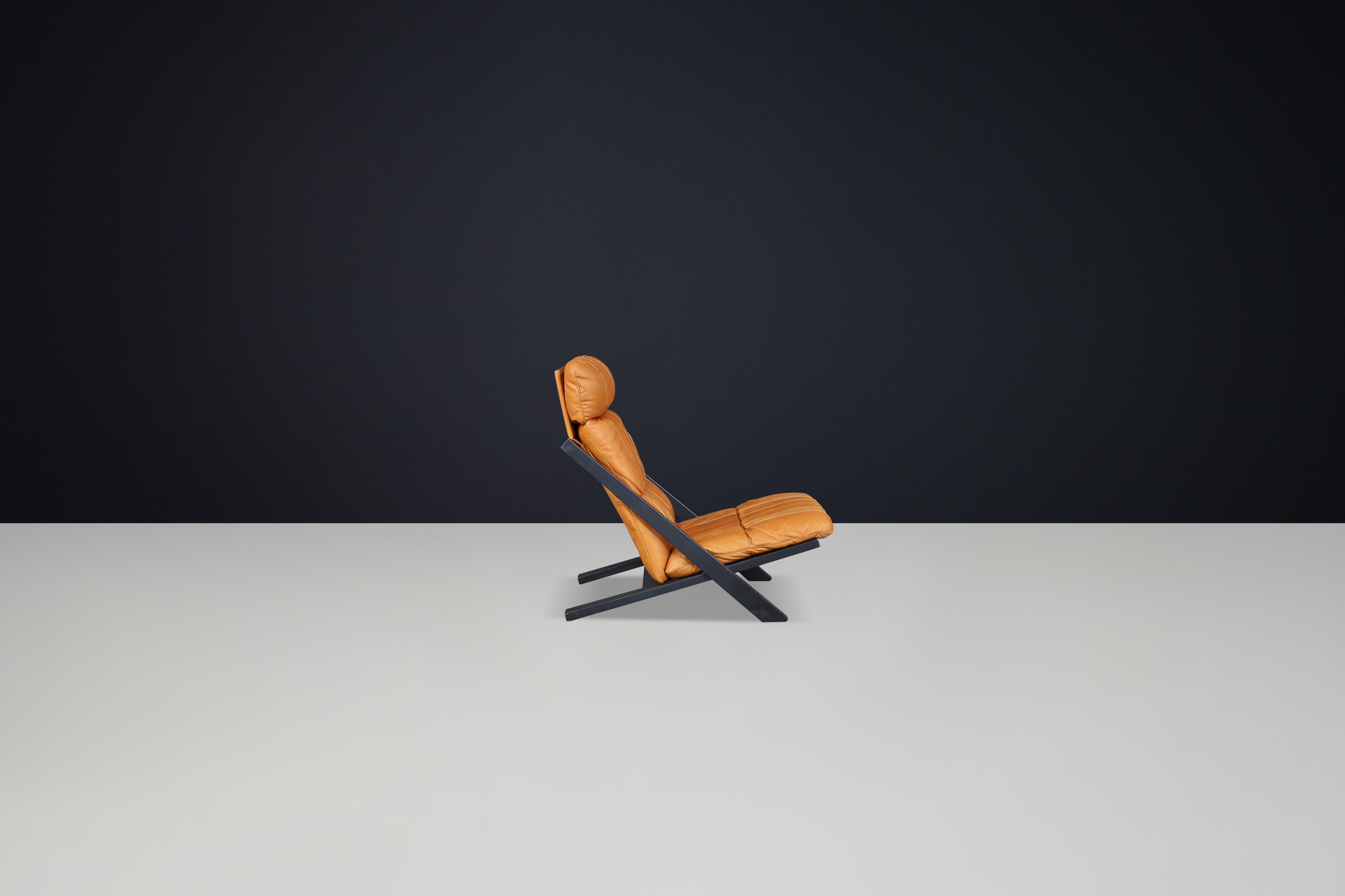 Ueli Berger for De Sede, lounge chair, wood, Cognac leather, Switzerland, 1970s.

This high-back lounge chair is produced by the Swiss manufacturer De Sede. It features an X-shaped frame made of black lacquered wood, which creates an interesting