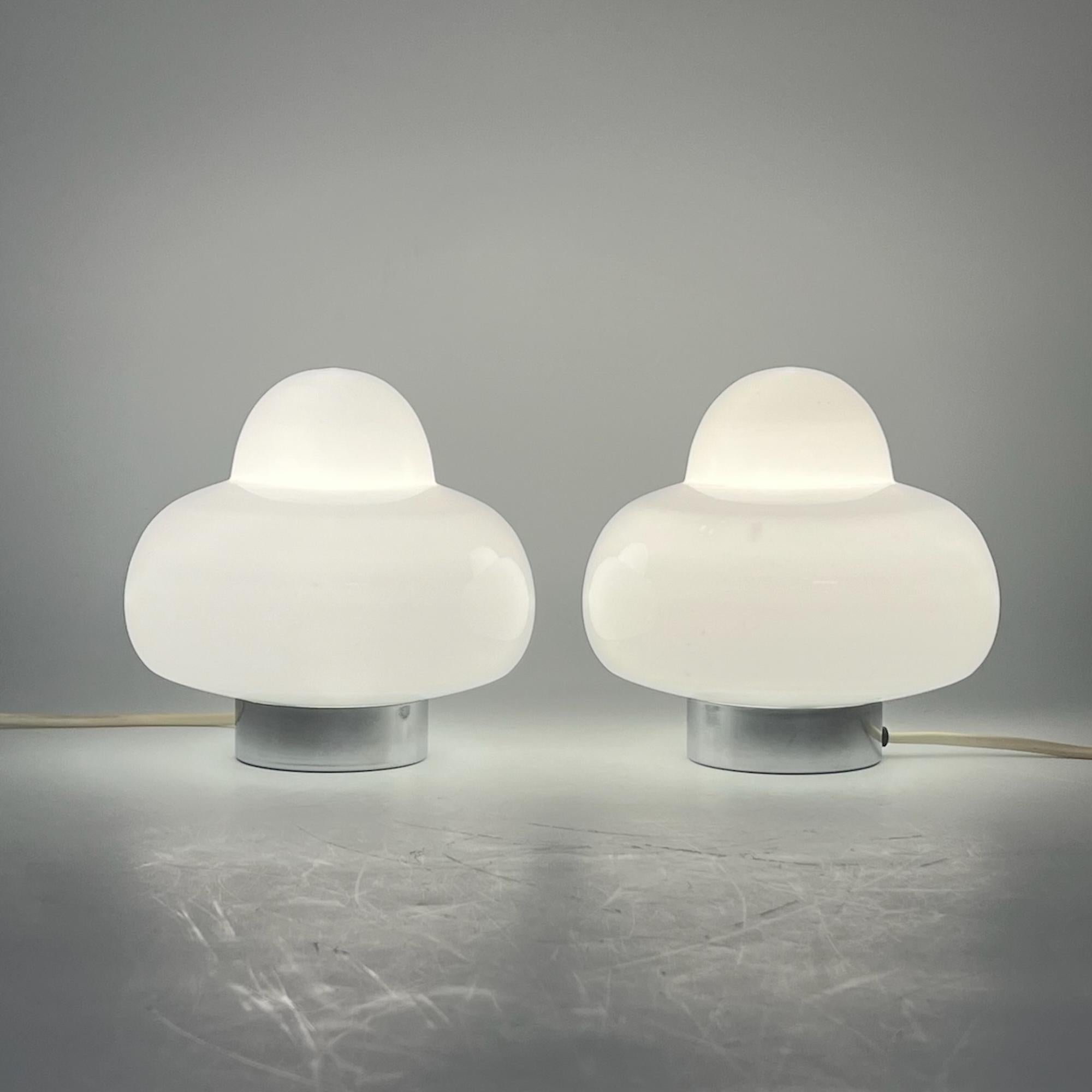 Step into the space age with this authentic Italian 1970s UFO lamp, meticulously crafted to evoke the iconic shape of flying saucers. Settle into the retro-futuristic ambiance as these lamps, with their sleek metal bases and translucent white glass