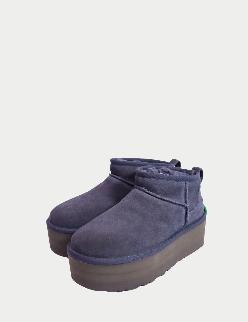 UGG Classic Mini Plateaustiefel in Navy Wildleder mit Shearling-Futter

Bleiben Sie gemütlich und stilvoll mit diesen authentischen UGG Classic Mini Platform Boots in navy. Diese knöchelhohen Stiefel aus hochwertigem Wildleder verfügen über das