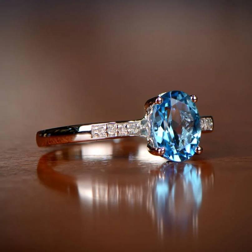 A captivating December birthstone ring adorned with a vibrant oval-shaped natural blue topaz, weighing around 1.10 carats. The topaz exhibits rich saturation, skillfully set in prongs within a handcrafted 14k white gold ring. Enhancing its allure,