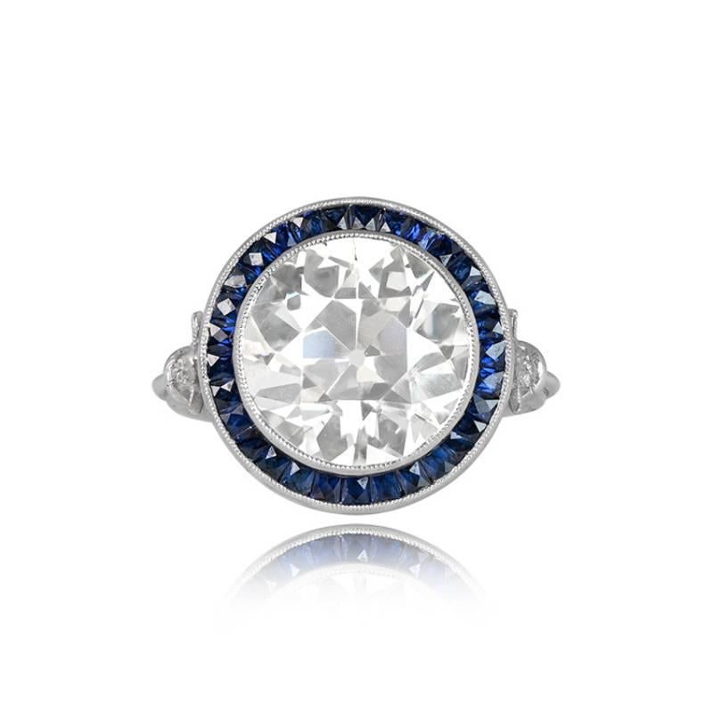 A beautiful ring features a 5.72ct old European cut diamond in a handmade platinum setting. The center diamond is encircled by a French-cut sapphire halo and adorned with additional diamonds on the shoulders. The gallery displays intricate openwork