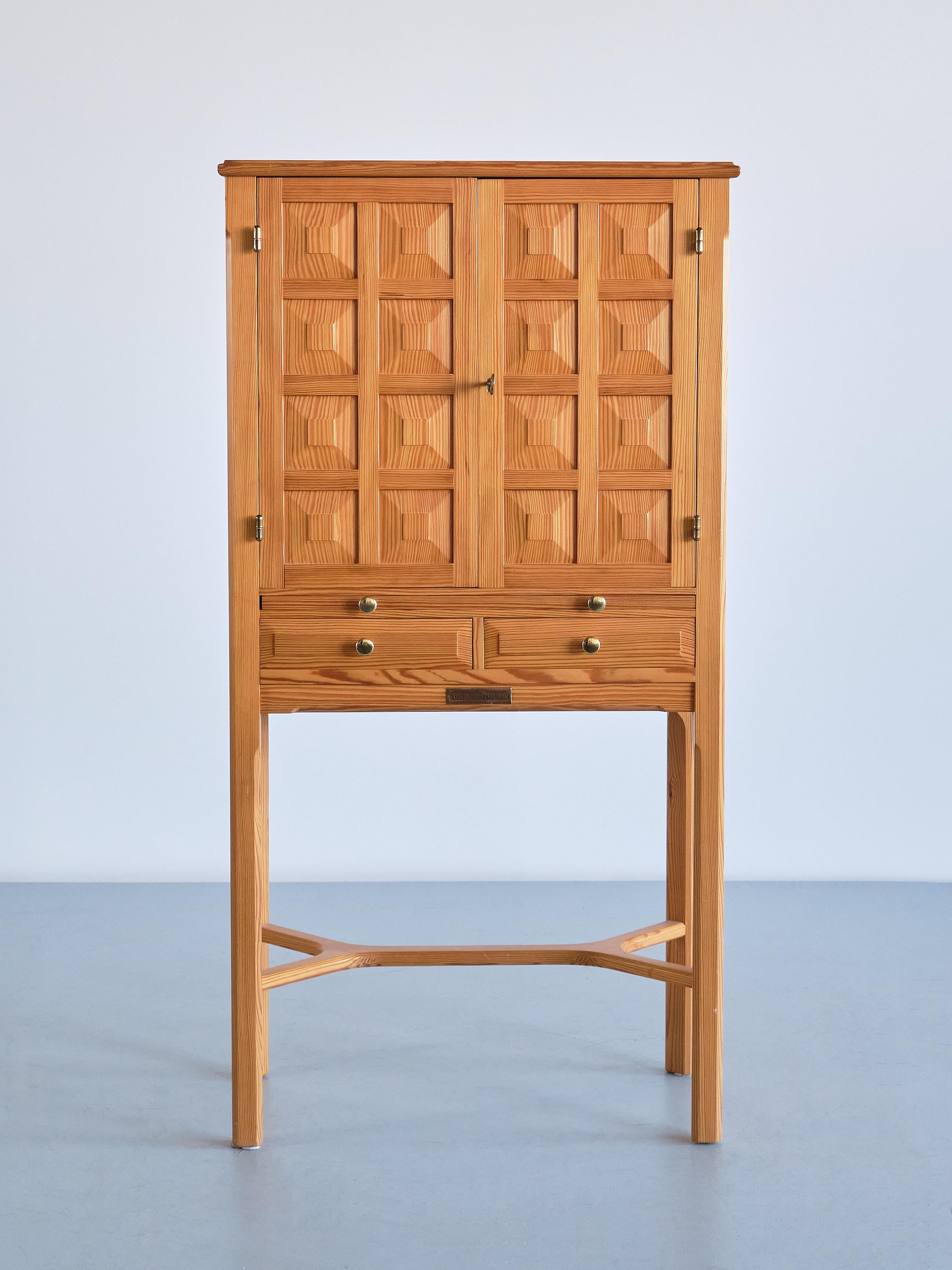 This striking cabinet was designed and produced by Ulf Ekdahl in Nybro, Sweden in 1979. 
The design is marked by the double doors, each panelled with eight squares with a centred, carved decoration. This creates a refined, geometric effect on the