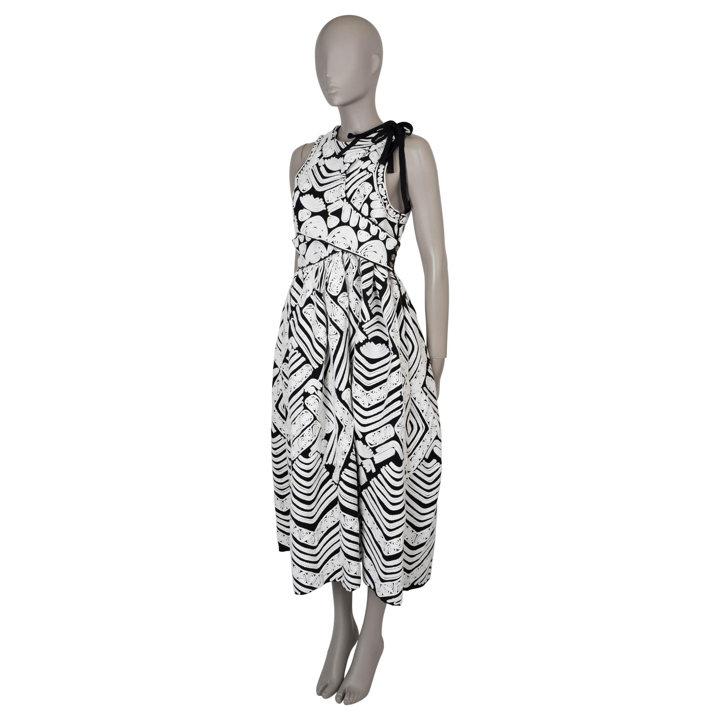 This 100% authentic Ulla Johnson Klea dress in black cotton showcases intricate white hand-woven cord embroidery, adding a touch of artisanal elegance. Designed in a flattering fit-and-flare silhouette with a midi length, the dress features a