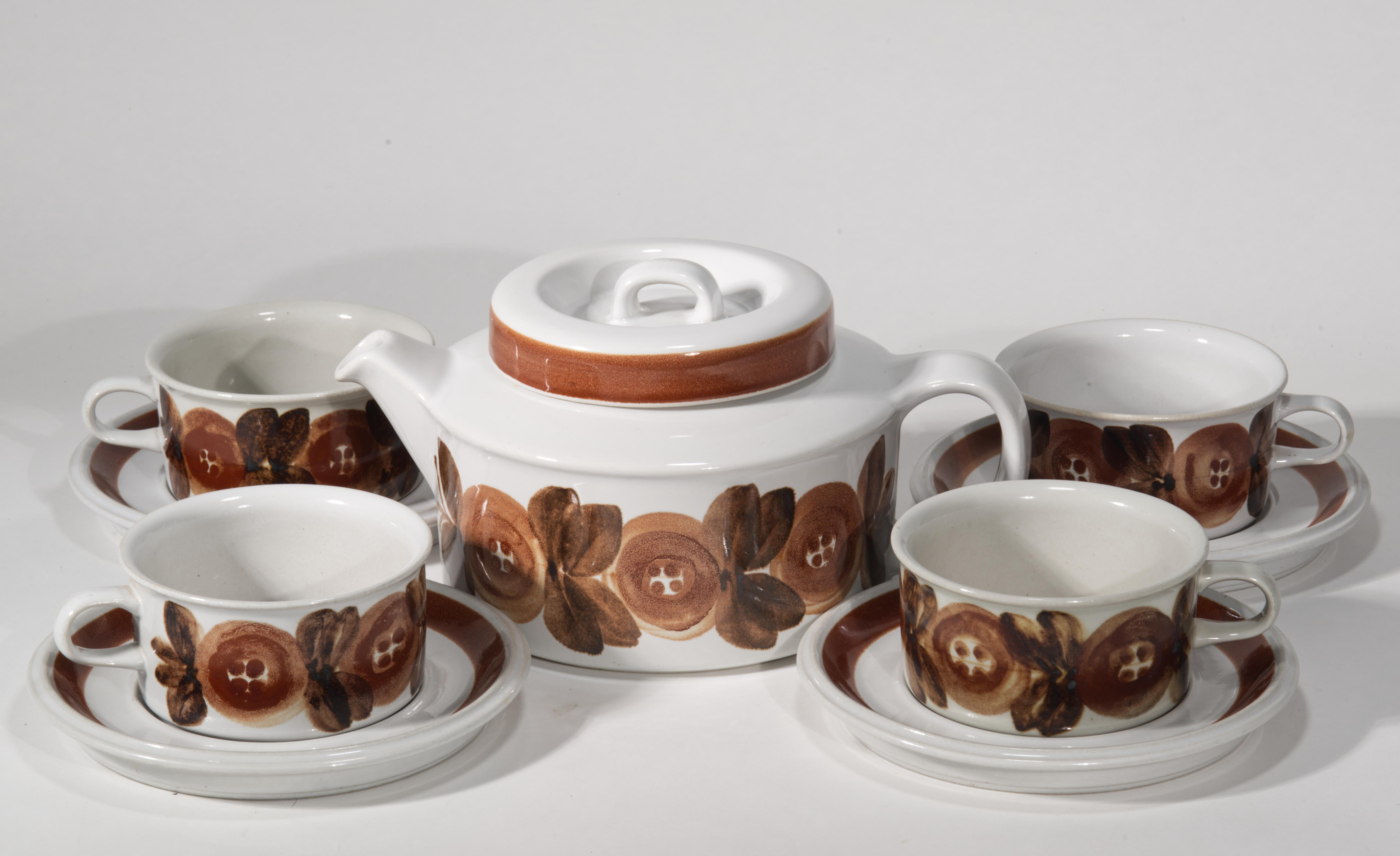  Vintage set of 4 flat cups with saucers and teapot is decorated with hand painted bands of flowers and stripes in brown palette. The Rosmarin series was created by Ulla Procopé in 1962; it was in production until mid 1970s. The designs are hand