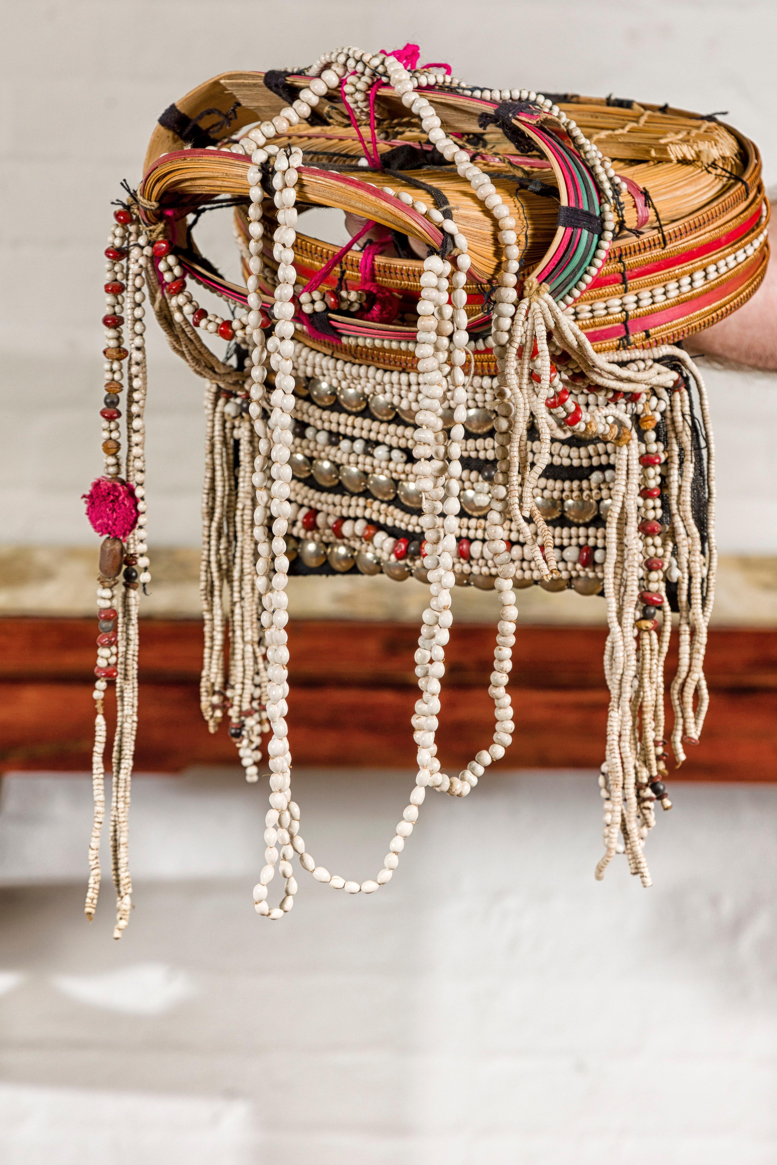 A Ulo Akha woman's Tribal headdress adorned with framework of bamboo, beads, pompons, seeds and other unique items. Immerse yourself in the rich cultural tapestry of Northern Thailand with this Ulo Akha woman's tribal headdress, a piece that
