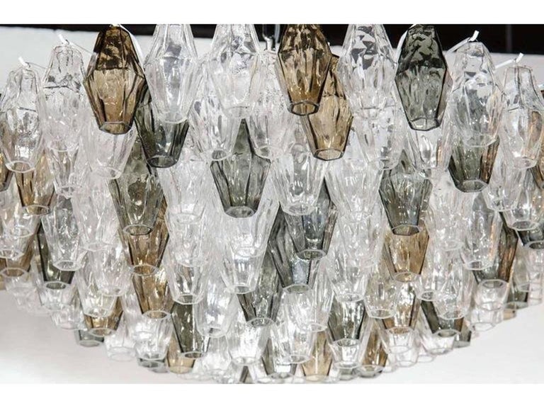 This ultra chic Murano glass chandelier in the manner of Venini features numerous handblown Murano glass polyhedral shades in a beautiful array of smoked, gray and clear glass. Each glass polyhedral shade is individually hung from its frame by hand.