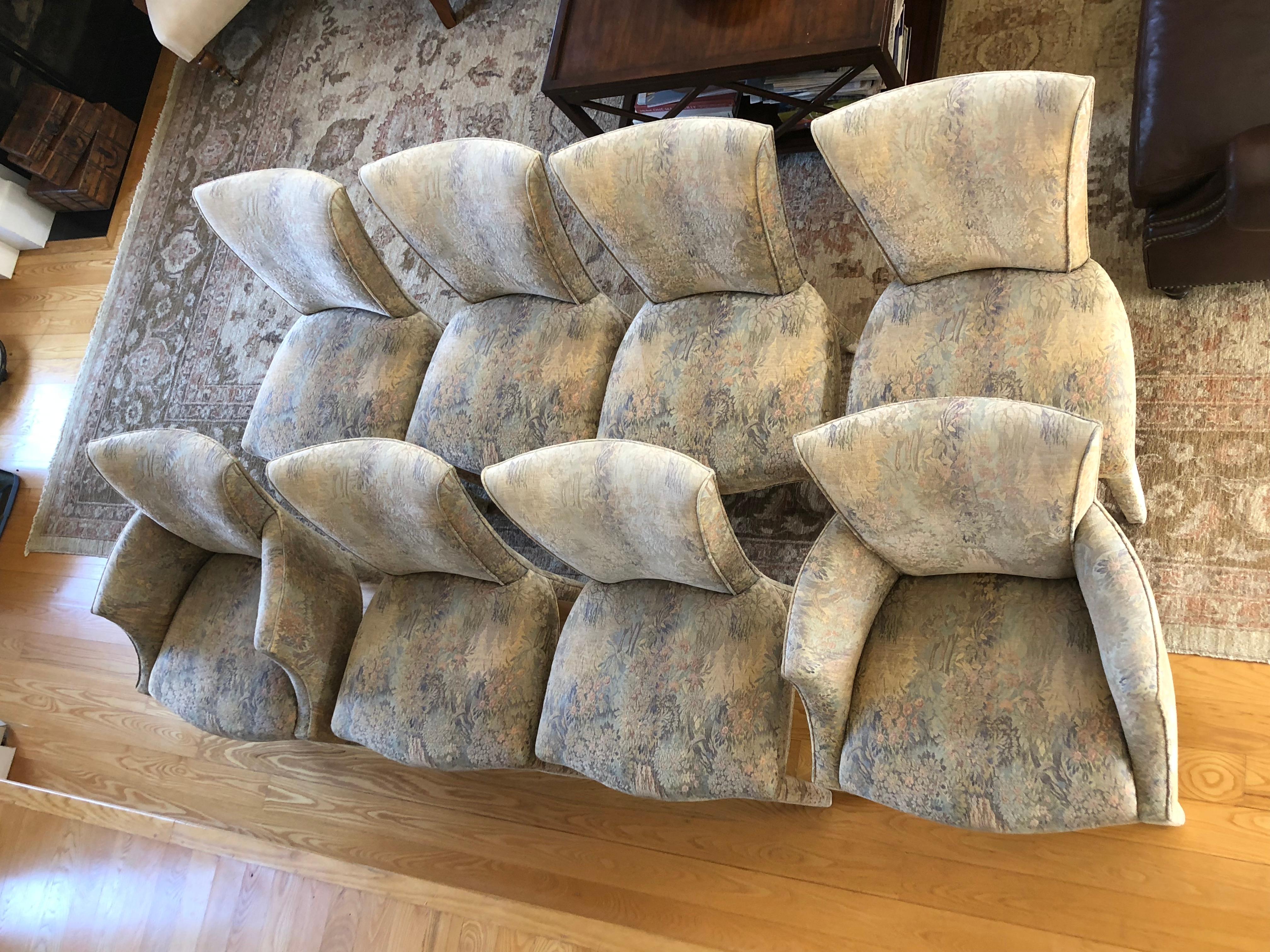 A sophisticated set of 8 dining chairs by Donghia fully upholstered in a raised tapestry with welt detail and legs that offer an understated elegance. There are two armchairs and 6 side chairs. The color palette is beigey grey mixed with hues of