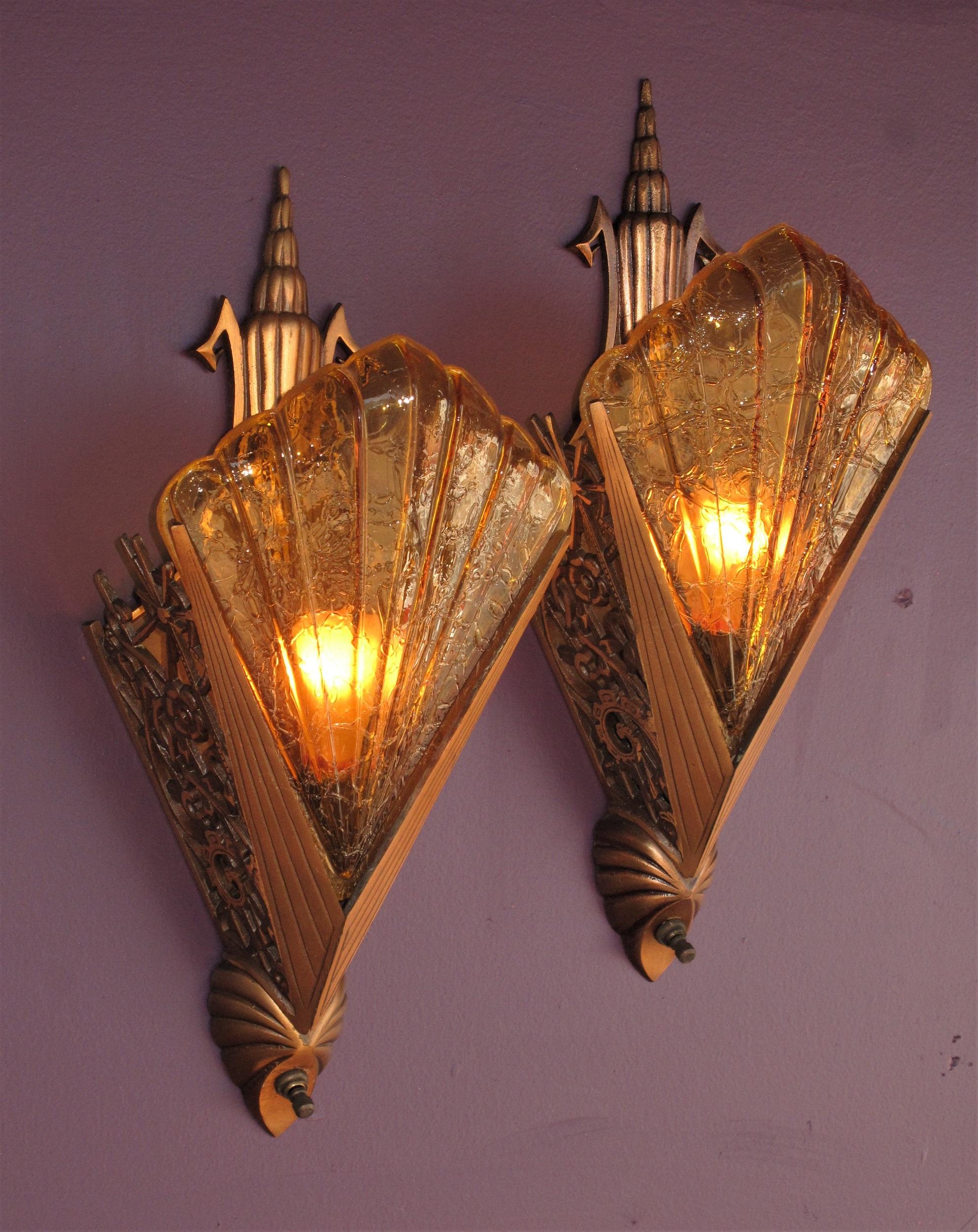 2 pair available. Priced per pair.
Rare & desirable vintage bronze deco sconces with honey colored slip shades .
One of the most sought after (and rare) pairs of vintage Art Deco wall sconce fixtures with original patina and shades. These American