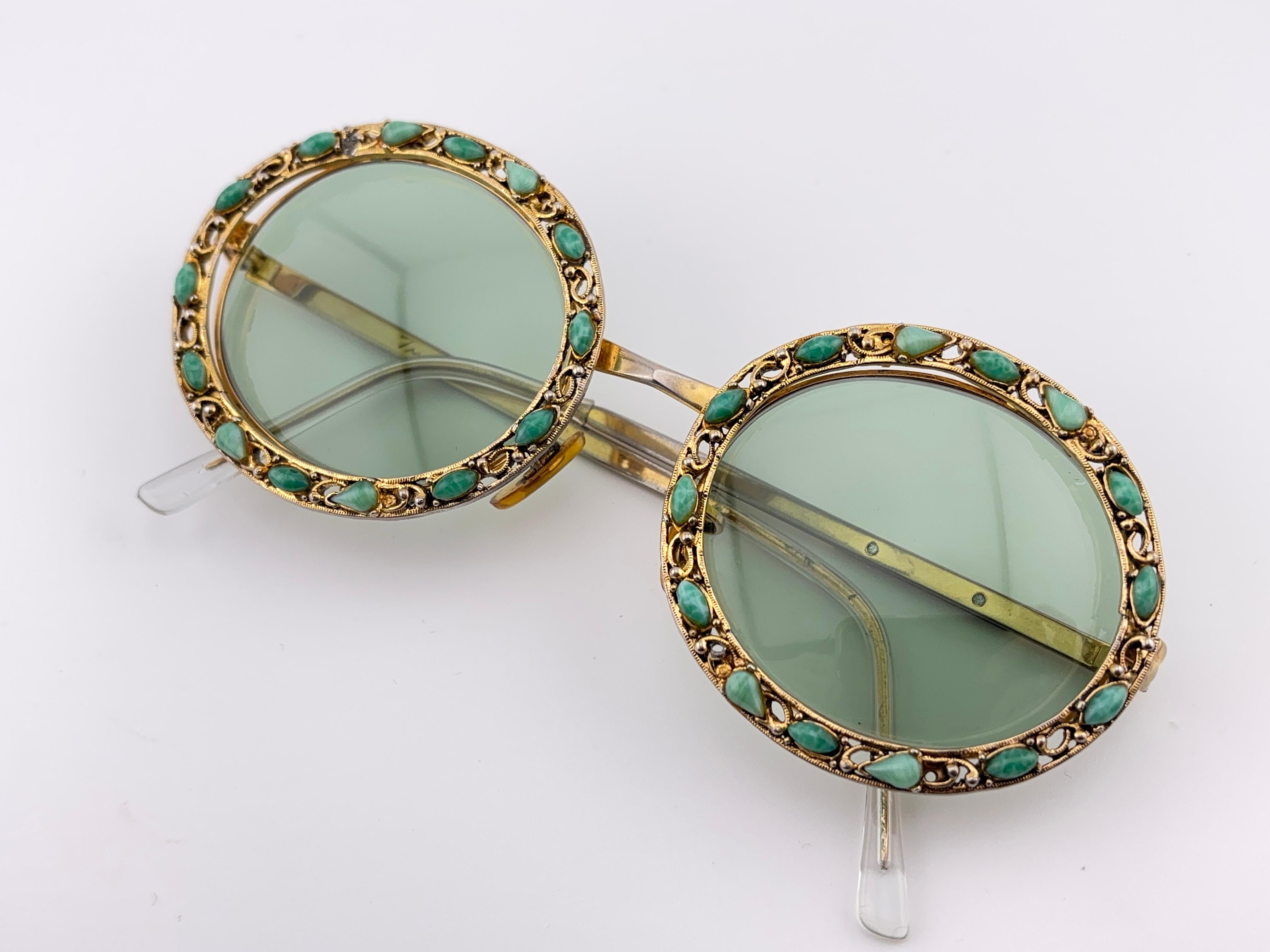 Il s'agit d'une pièce rare, non seulement pour sa valeur esthétique, mais aussi pour son importance dans l'histoire des lunettes de soleil et de la mode.   
Cadre en fonte délicatement orné d'émail et de pierres précieuses vertes. 
Veuillez noter
