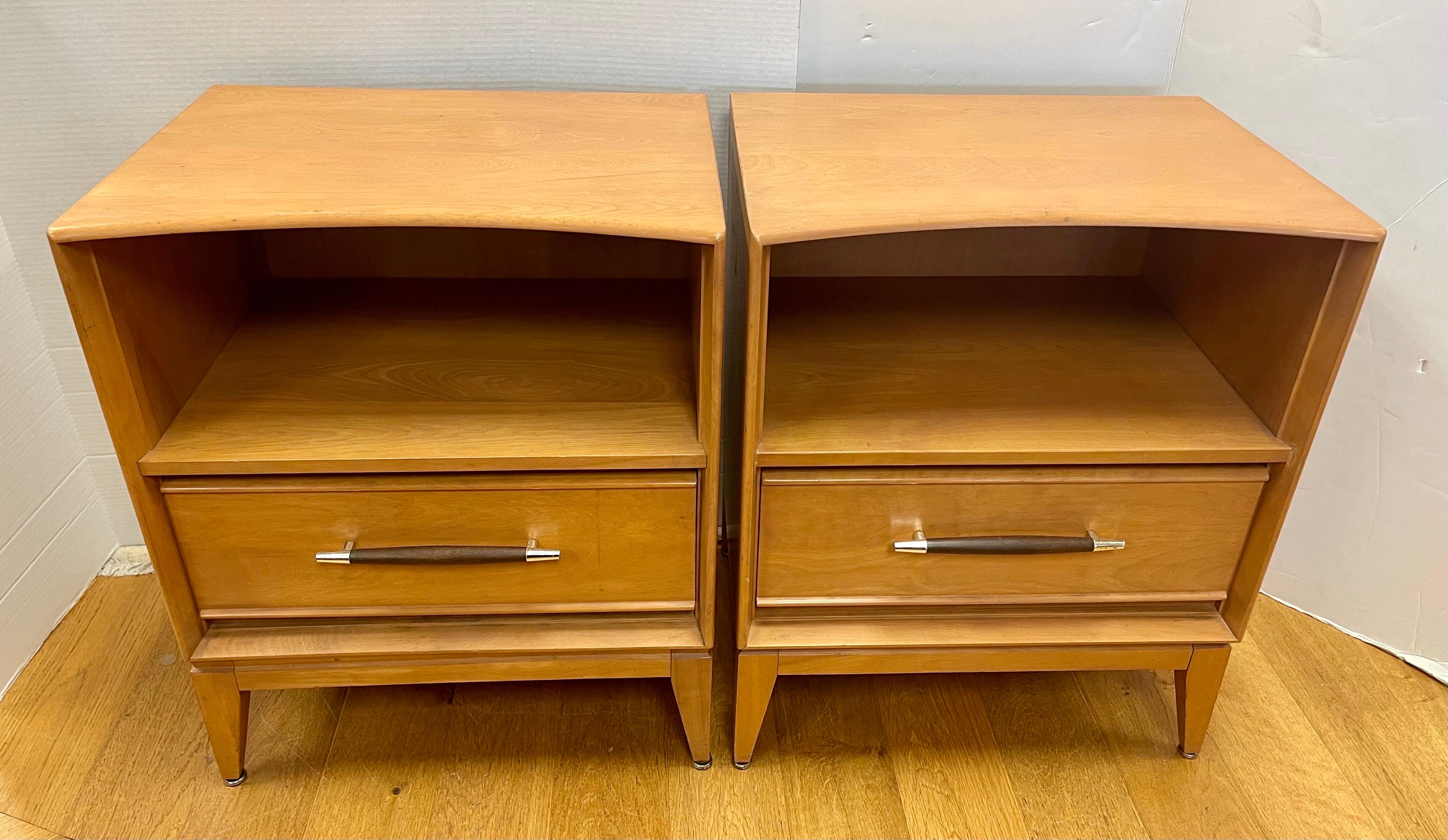 Pair of signed vintage Heywood Wakefield one drawer nighstands in champagne finish with sculptural walnut with brass drawer pulls. Date stamped 1955. Not your cookie cutter Heywood Wakefield. 
See our other listings for tall chest and triple dresser.