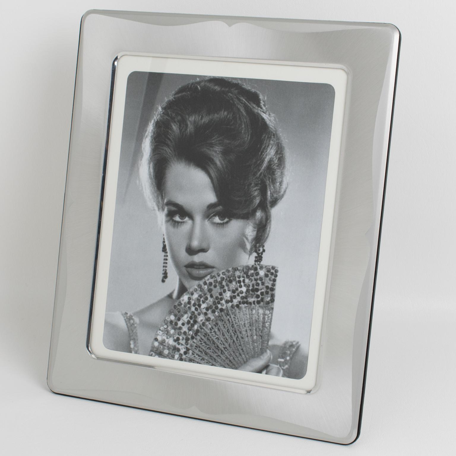 Le designer italien Umberto Mascagni, originaire de Bologne, a conçu ce cadre photo séduisant dans les années 1970. La pièce arbore de l'aluminium argenté aux motifs brossés et givrés, avec un design ondulé sur tout son pourtour et des angles