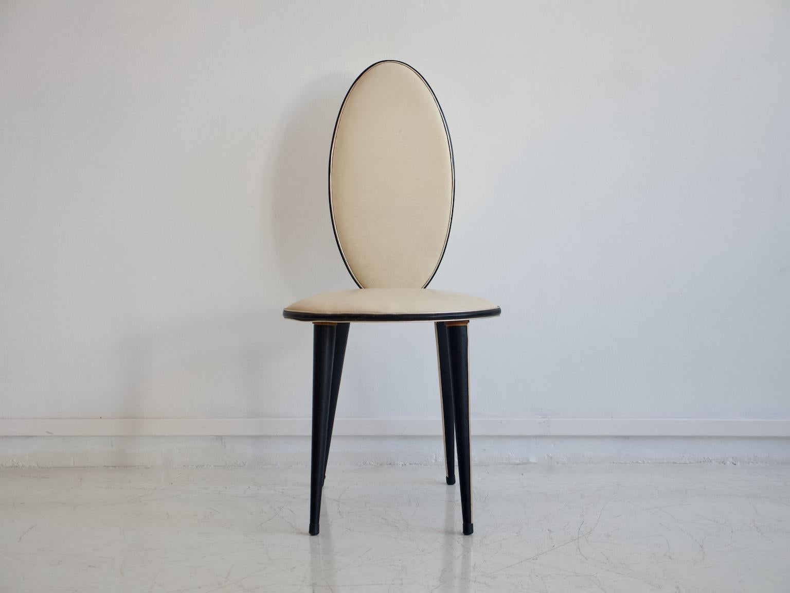 Chair from the 1950s, Italian design by Umberto Mascagni. Conical wooden legs covered with black vinyl and with inlaid gold metal trim. Seat and back covered in cream white vinyl with black edging. Traces of wear commensurate with age, some cracks