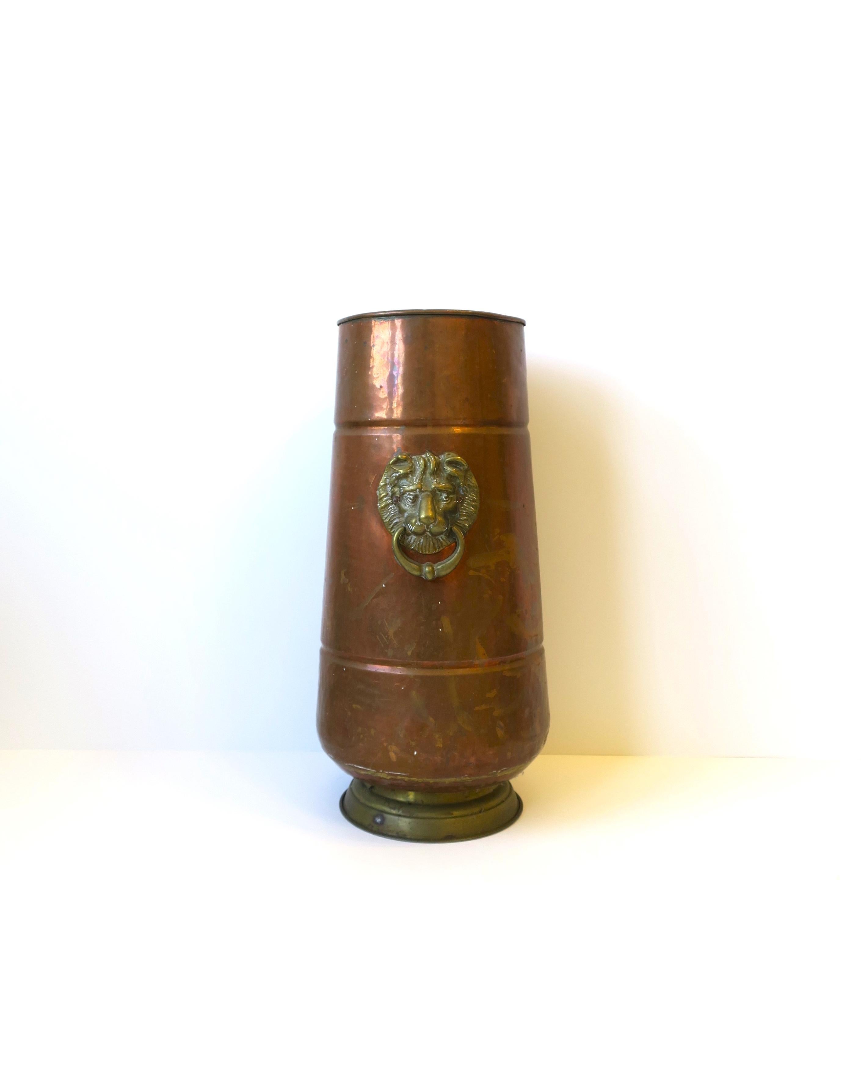 A copper and brass umbrella holder stand in the Regency style with lion head design, circa early to mid-20th century, Europe, Netherlands. Piece has a hand-hammer copper design with brass lion head and loop detail on two sides, finished with a brass