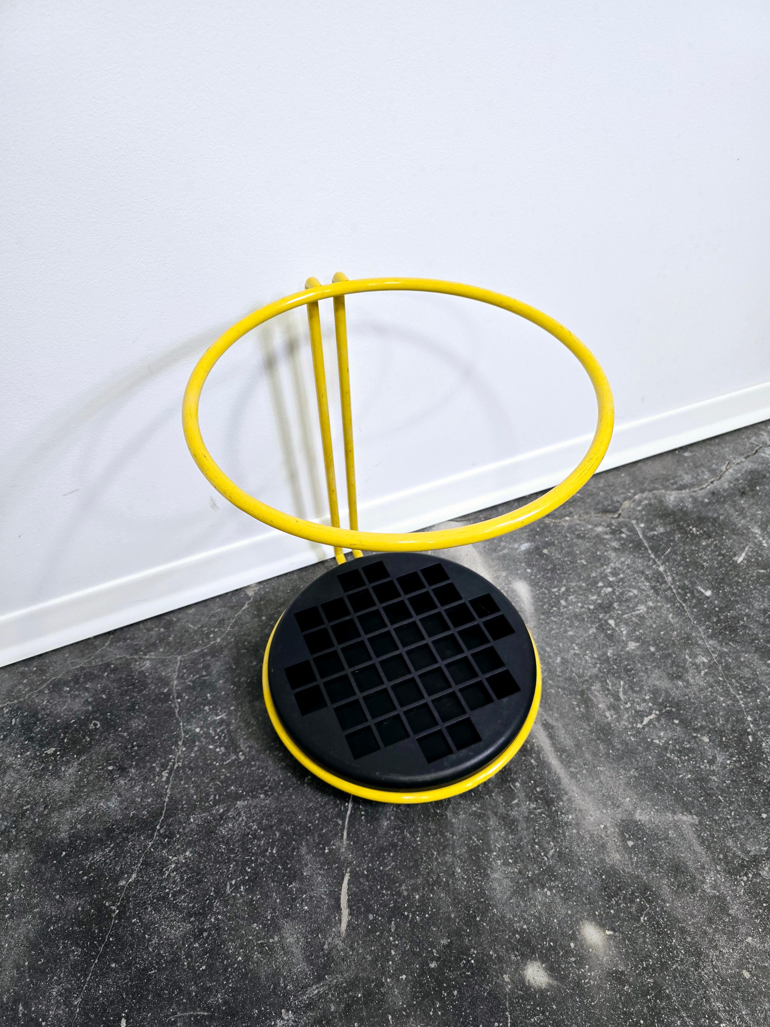 Postmodern umbrella stand by Magis, design by Boccato Gigante Zambusi.

The contrast between black and yellow is striking. The round steel is painted yellow and clamps into a black polypropylene base.

The finely crafted shape made of rods appears