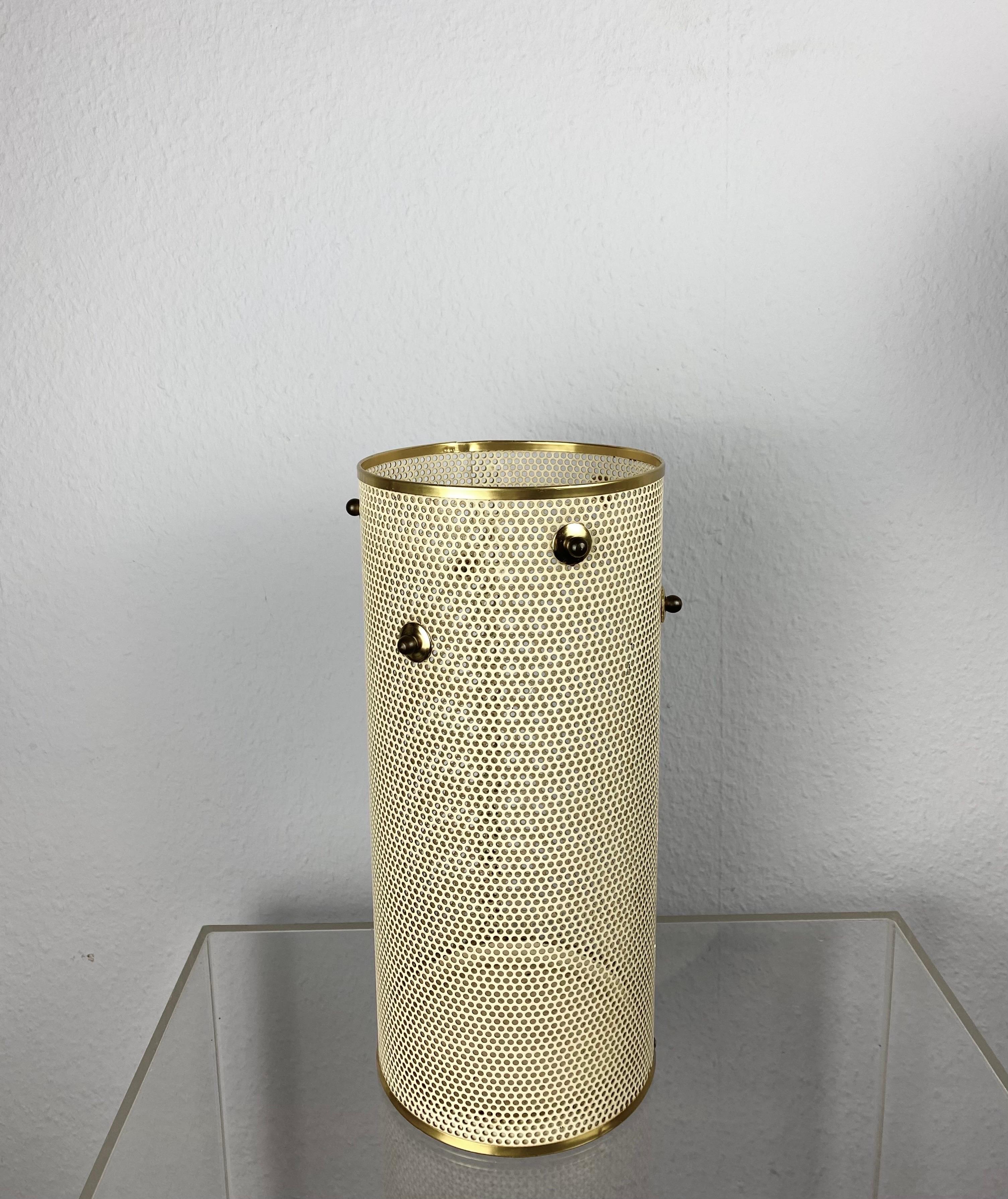 A rare umbrella stand or cylindrical deko-vase in perforated metal with nice brass Details from the 50s.
The stand with the original laquered steel has a beautiful patina and is in a good vintage condition.