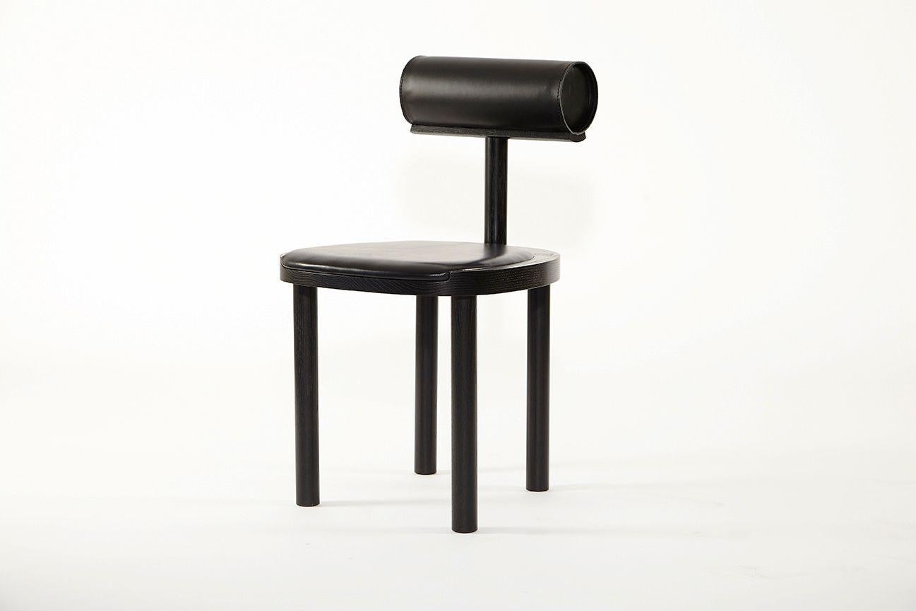 Una chair upholstered by Estudio Persona
Dimensions: W 45.7 x D 48.3 x H 78.8 cm
Materials: Solid ash, stained black finish, black vegetable leather and black leather

Dining chair in solid ash, stained black finish, upholstered back bolster in