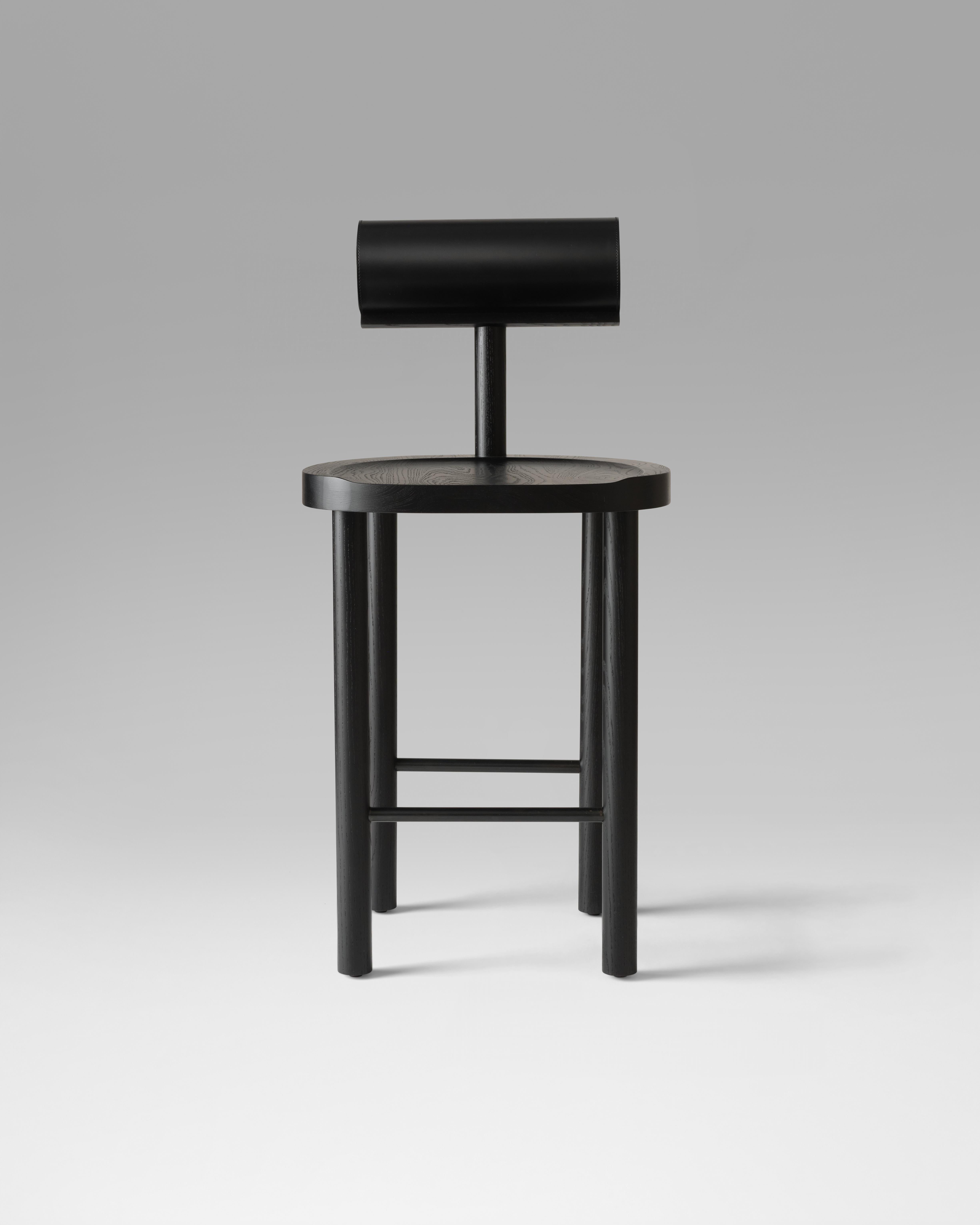 The UNA counter stool intersects a round wooden seat and legs with a leather upholstered cylindrical back. Using these fluid shapes allows greater focus on the details of the wood grain and pristinely stitched leather top. 

Made of solid black