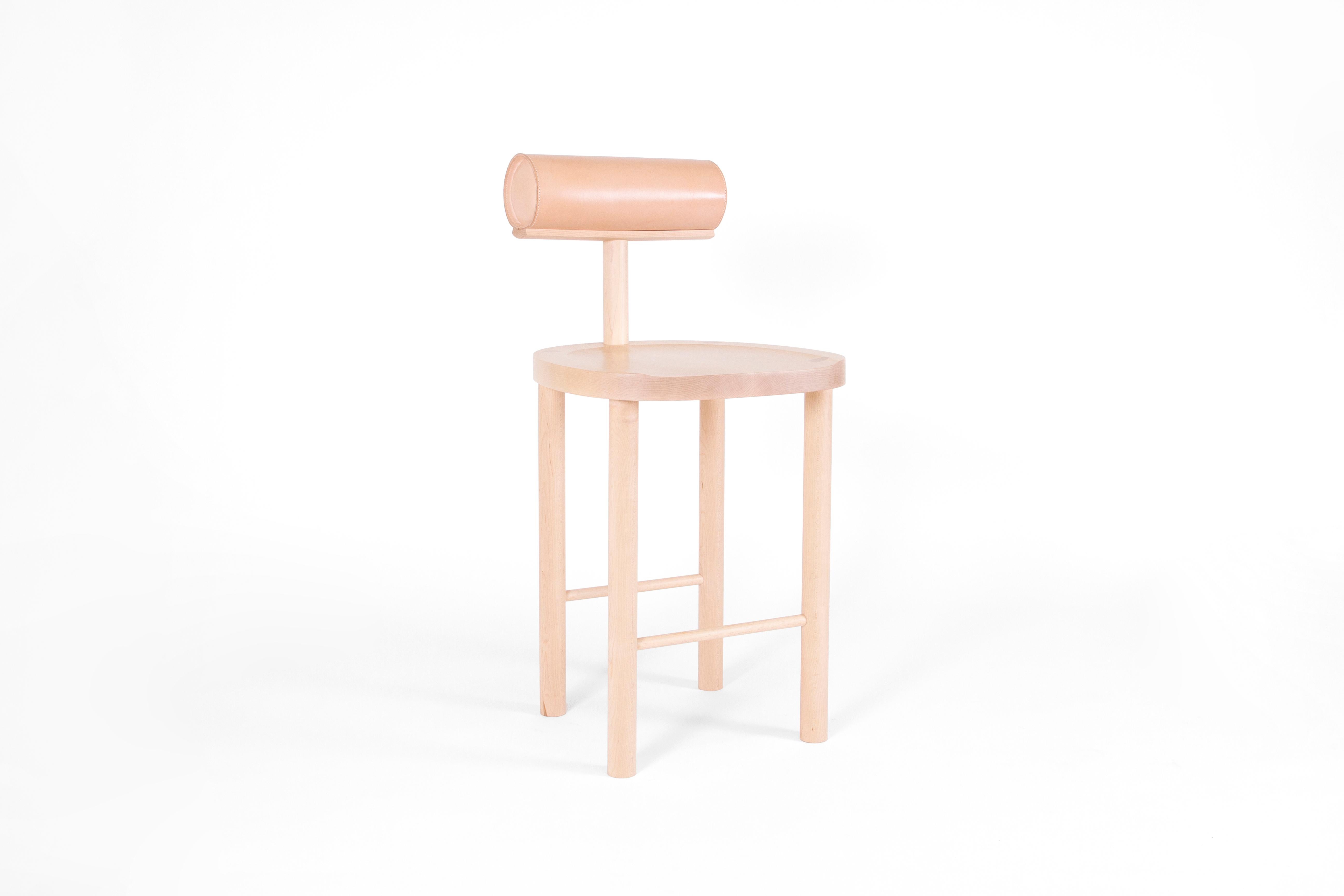 The UNA counter stool intersects a round wooden seat and legs with a leather upholstered cylindrical back. Using these fluid shapes allows greater focus on the details of the wood grain and pristinely stitched leather top. 

Made of solid maple