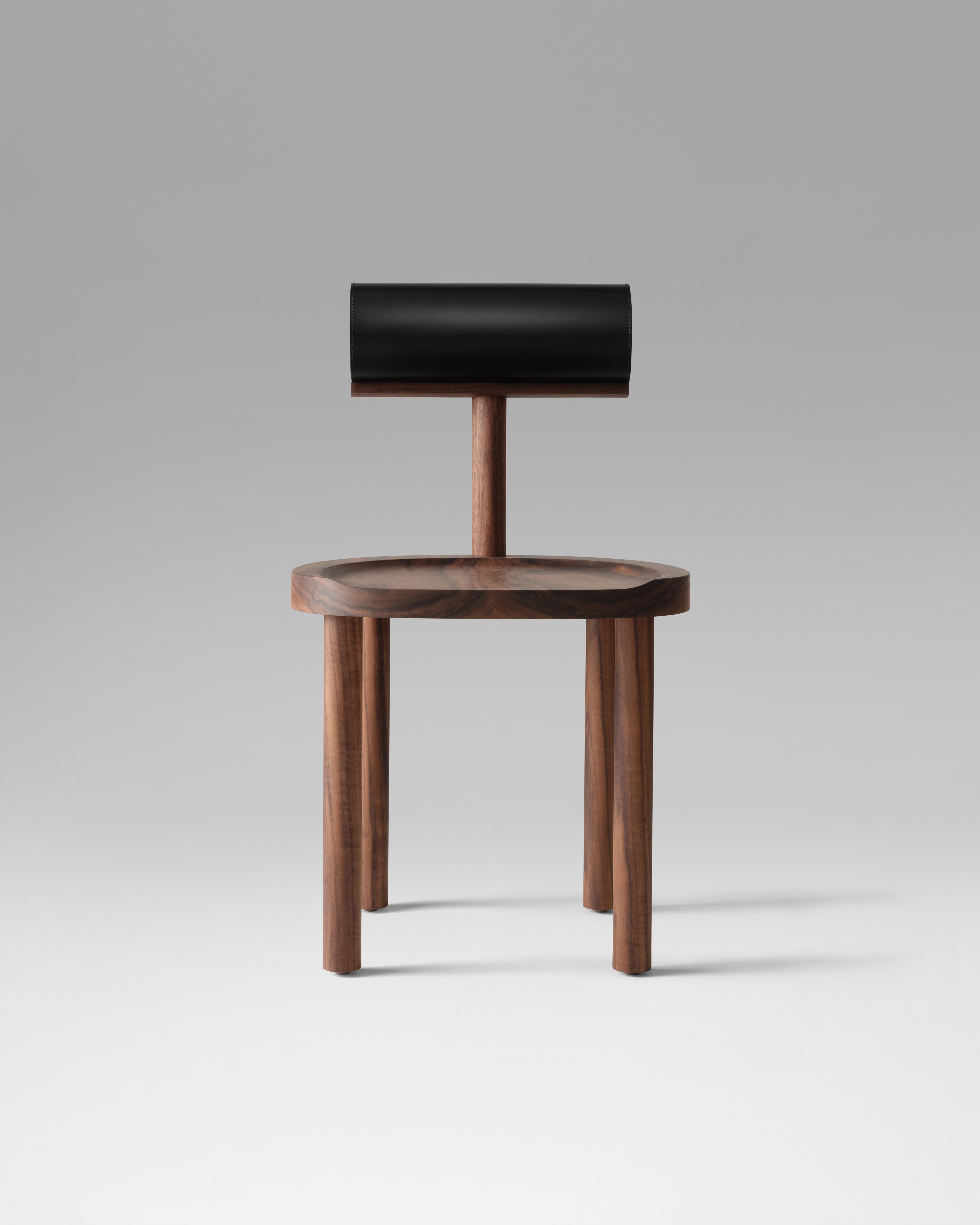 Der UNA-Stuhl verbindet eine runde Sitzfläche und Beine aus Holz mit einer ledergepolsterten zylindrischen Rückenlehne. Die Verwendung dieser fließenden Formen ermöglicht eine stärkere Konzentration auf die Details der Holzmaserung und der makellos